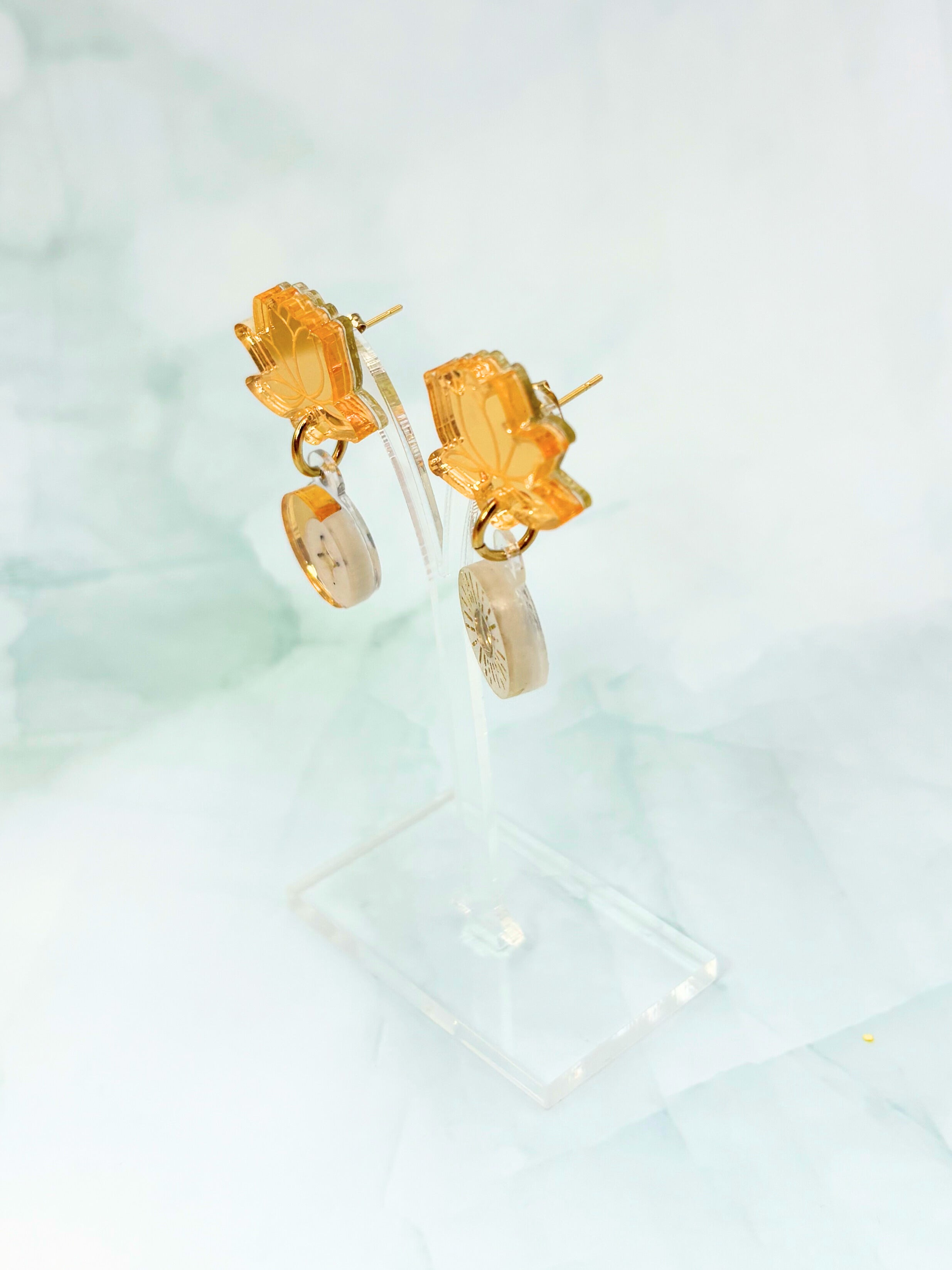 Gold earrings with orange gemstones on a light blue background