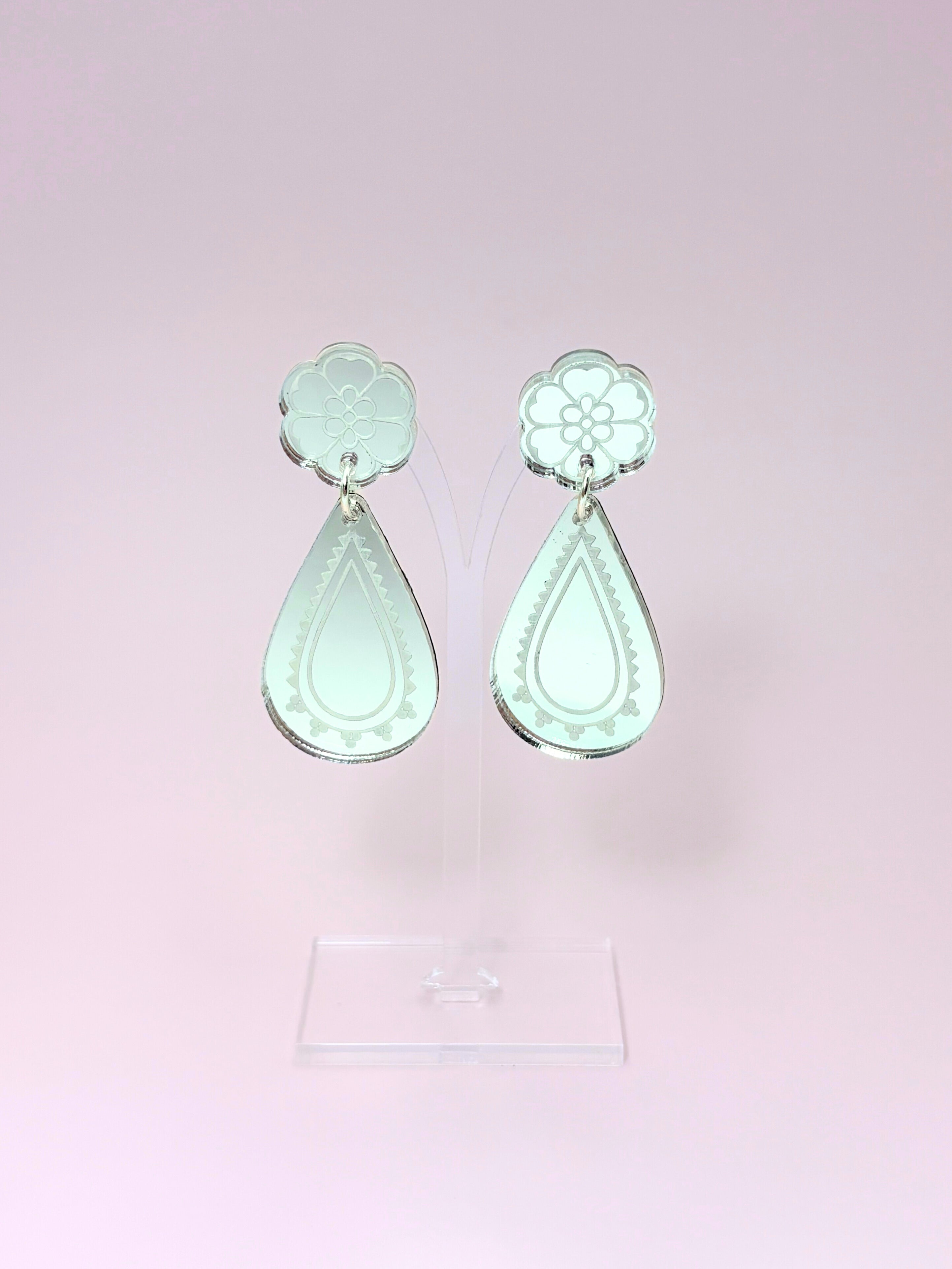 Pair of silver teardrop earrings on a pink background