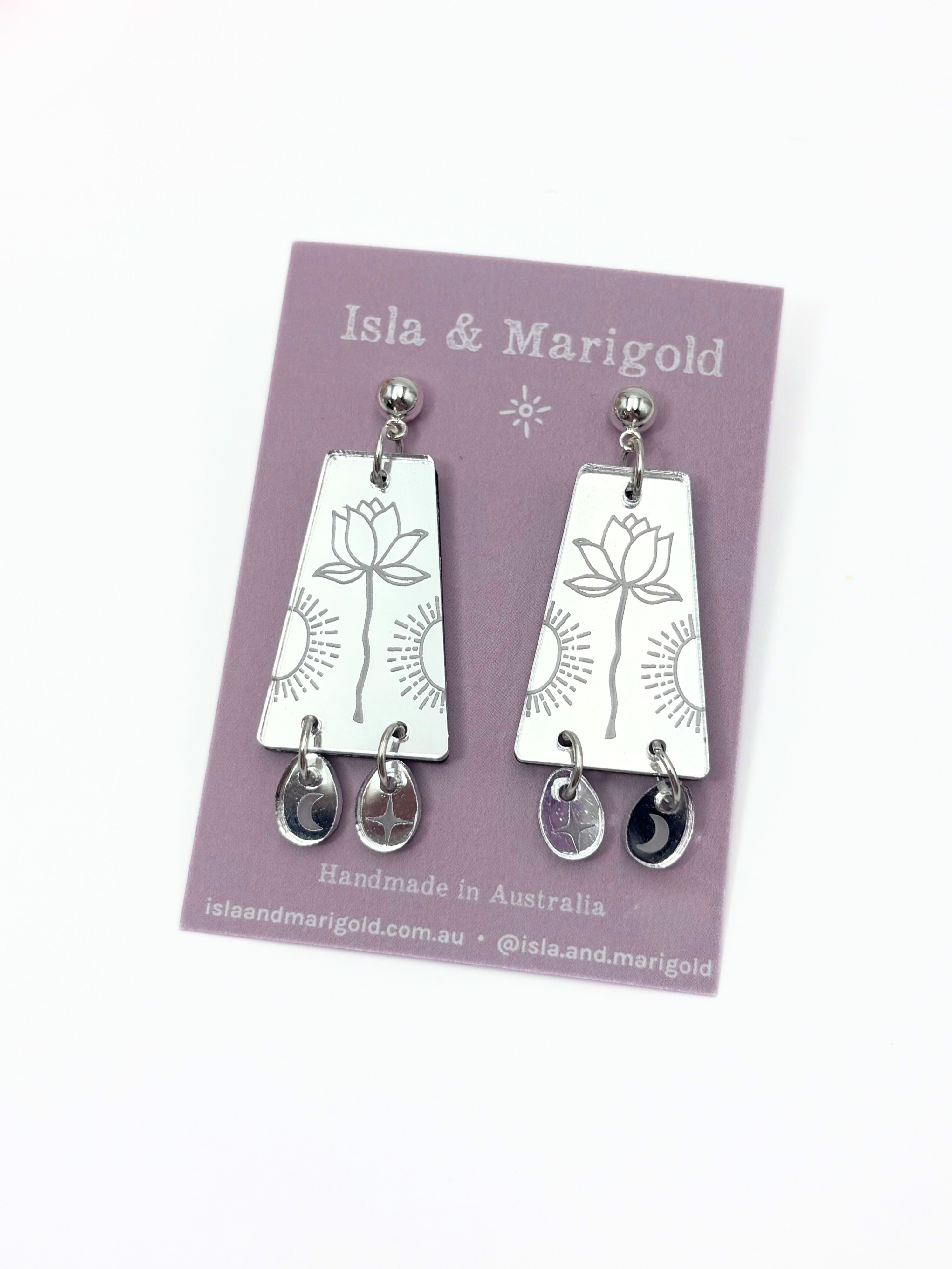 Silver earrings on a pink card with 'Isla & Marigold' branding.