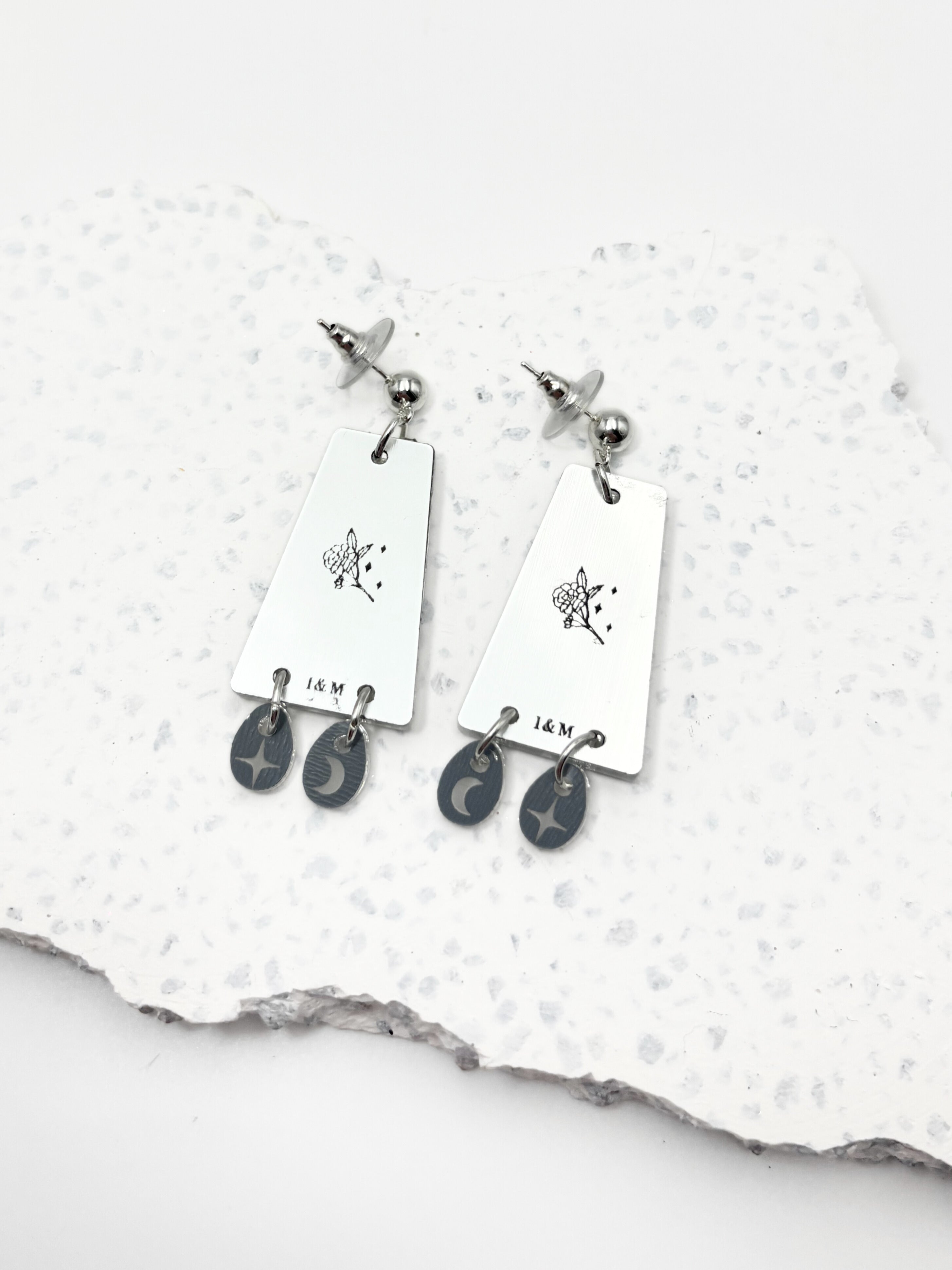 Pair of earrings with hanging charms on a textured white surface