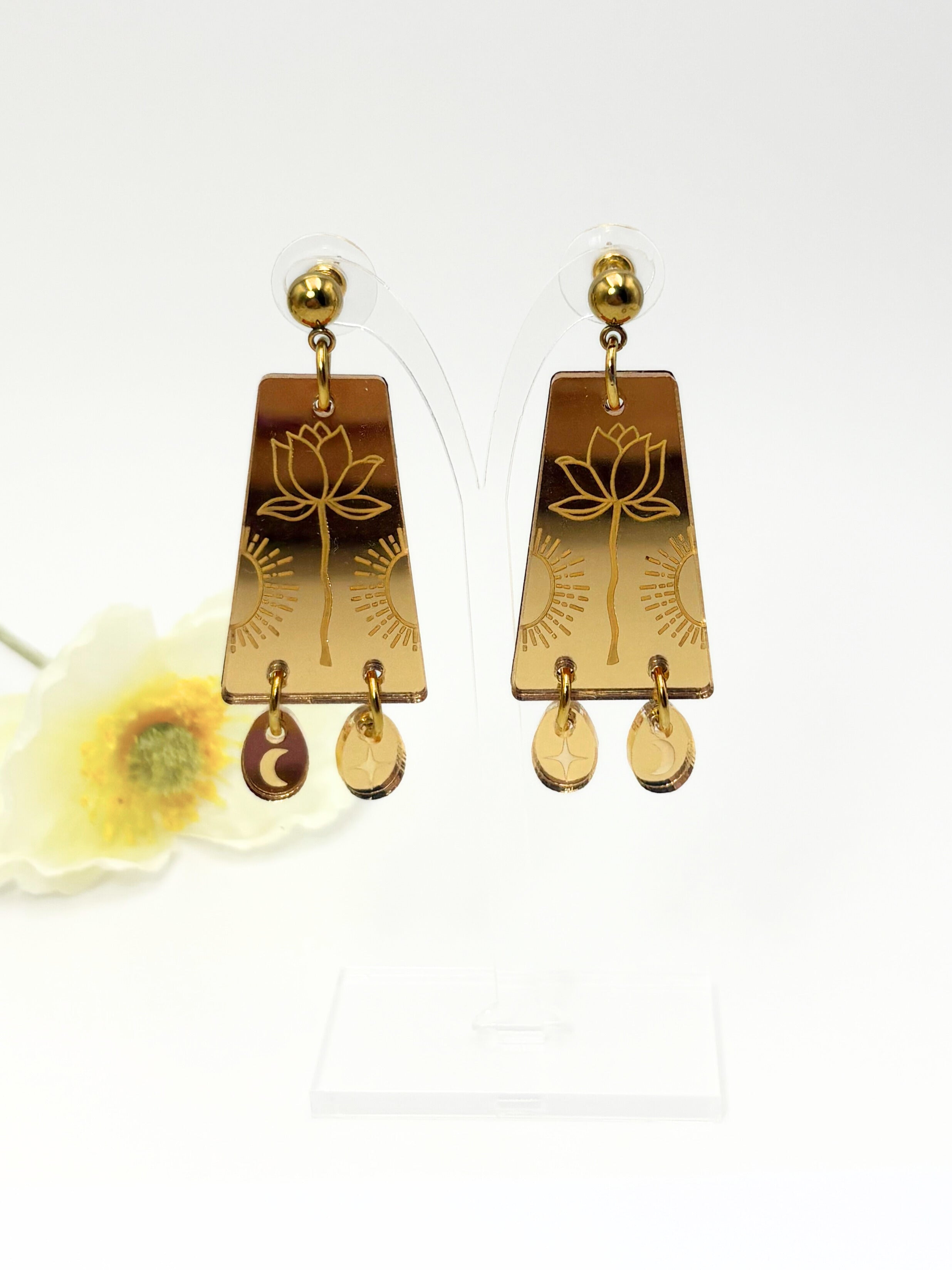 Gold earrings with lotus design on a white background