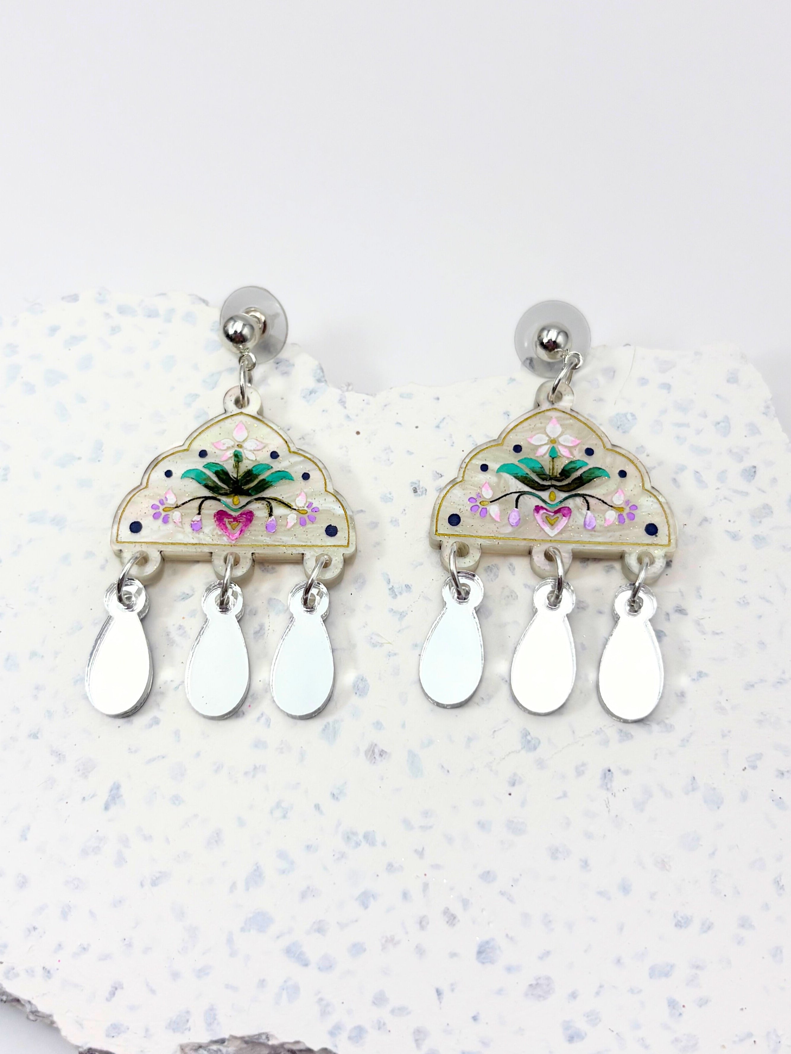 Decorative earrings with floral design on a textured white surface