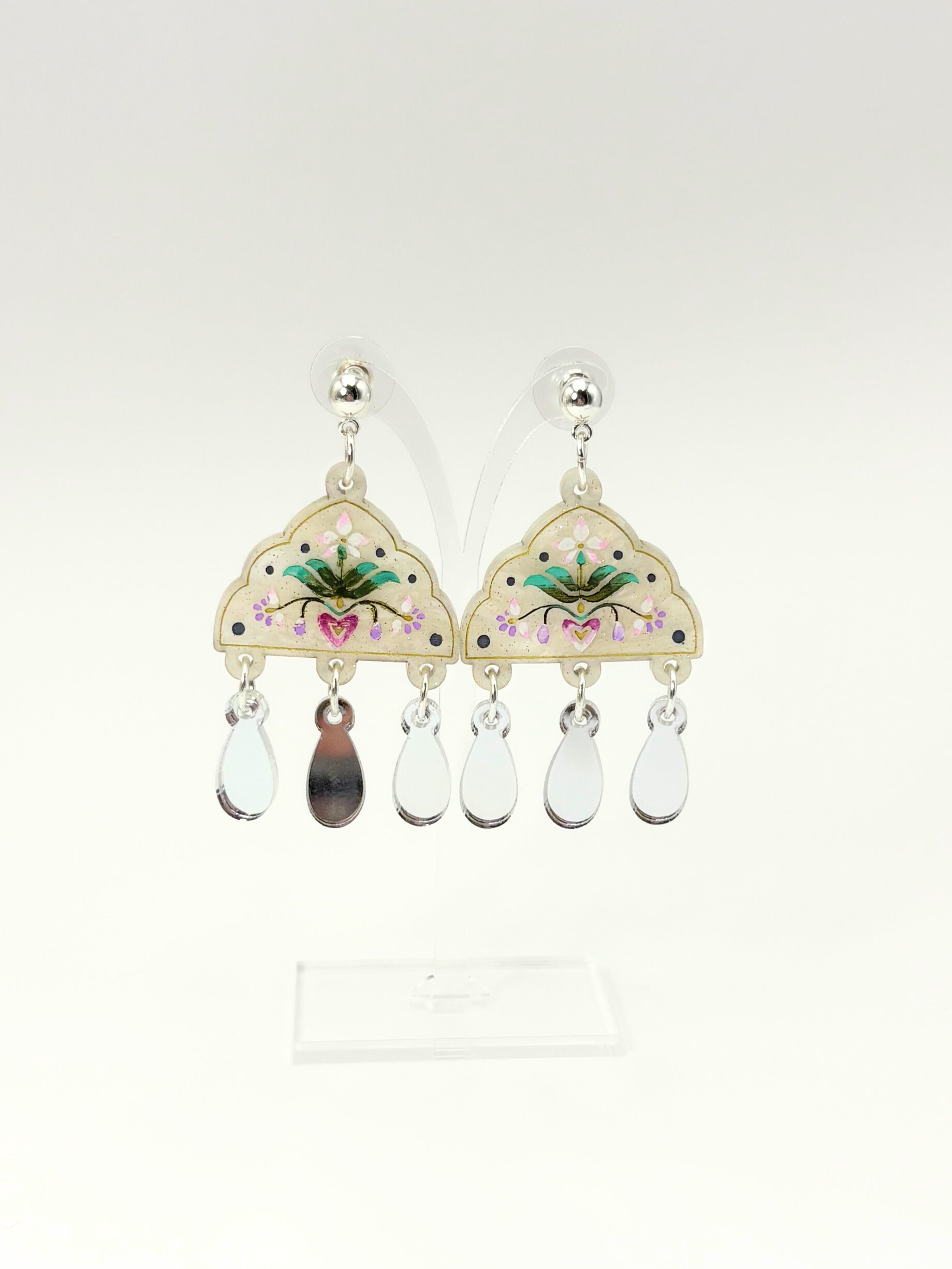 Pair of earrings with floral designs and teardrop-shaped beads on a white background