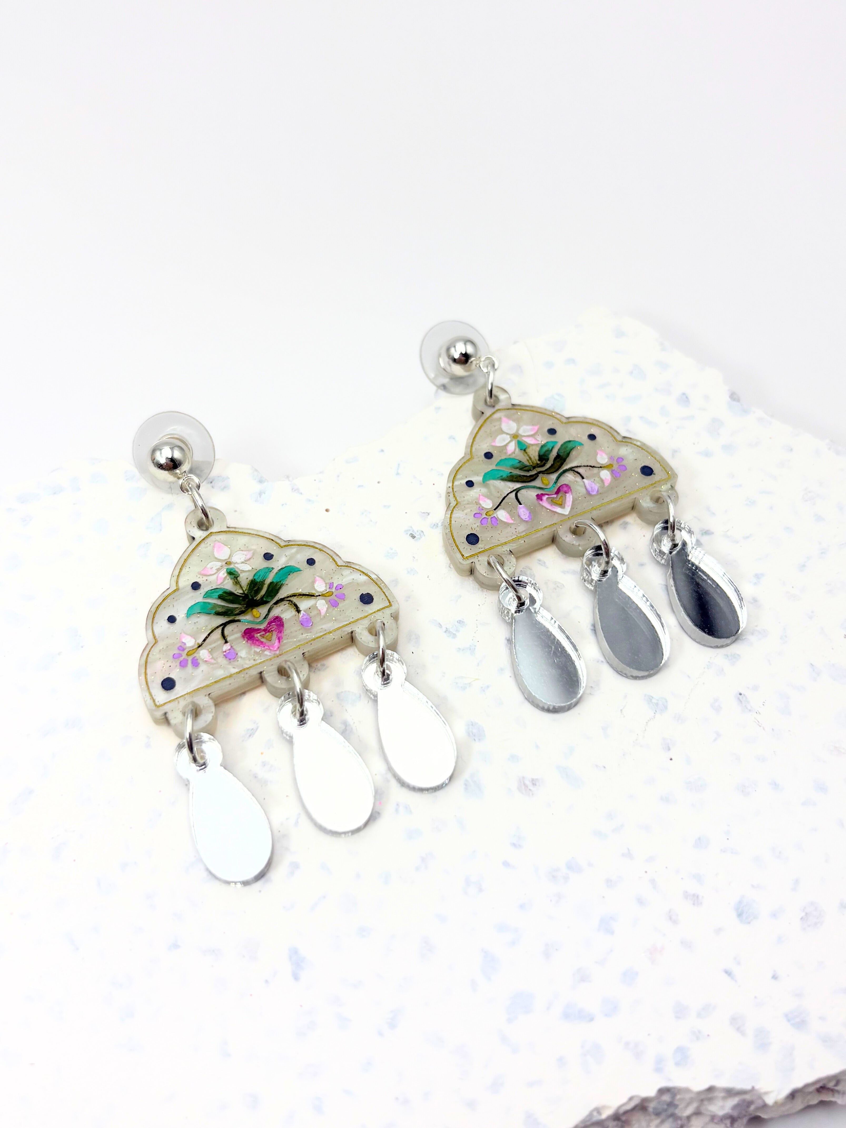 Pair of earrings with floral designs on a white background