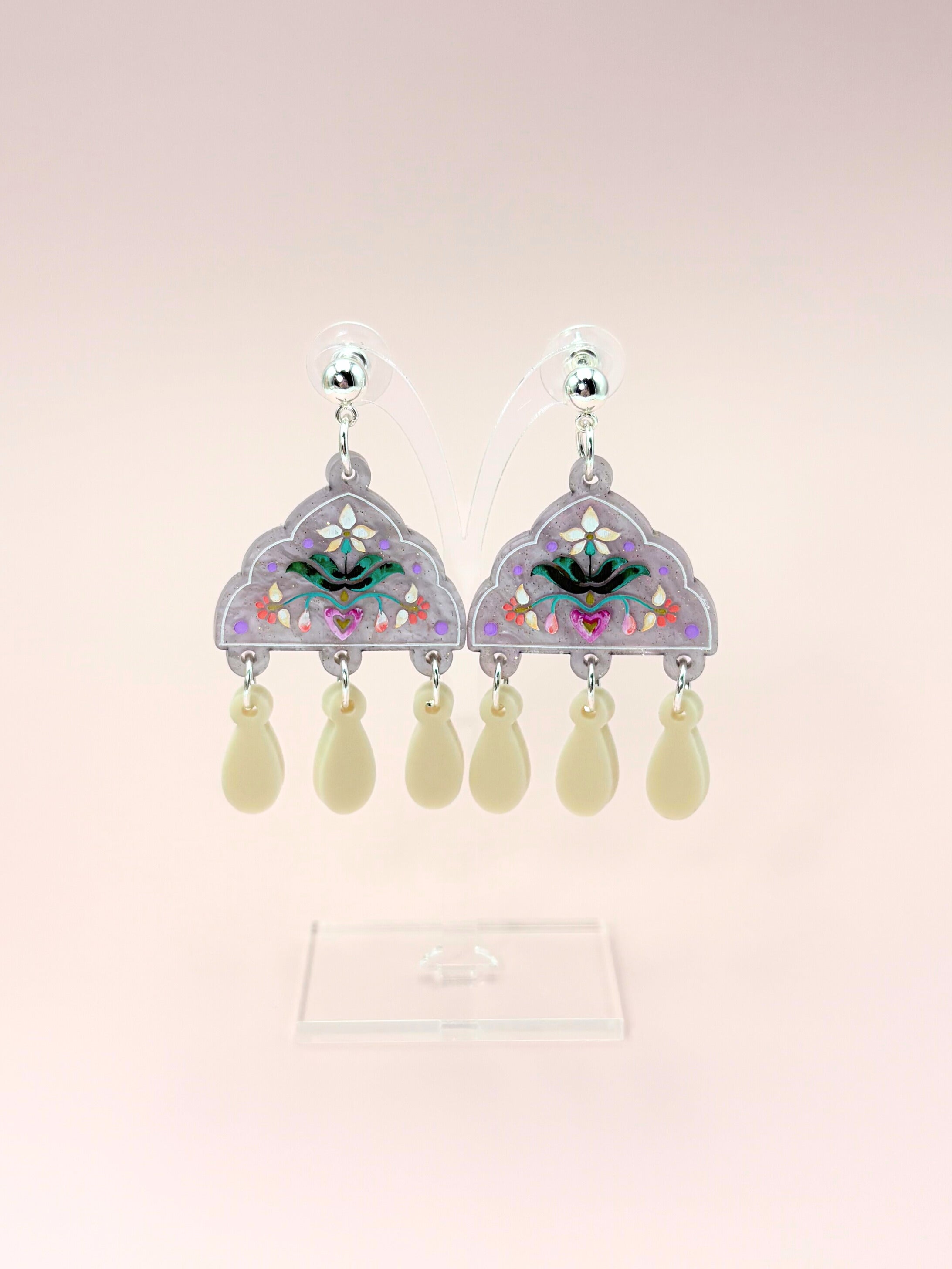 Pair of earrings with decorative elements on a light pink background