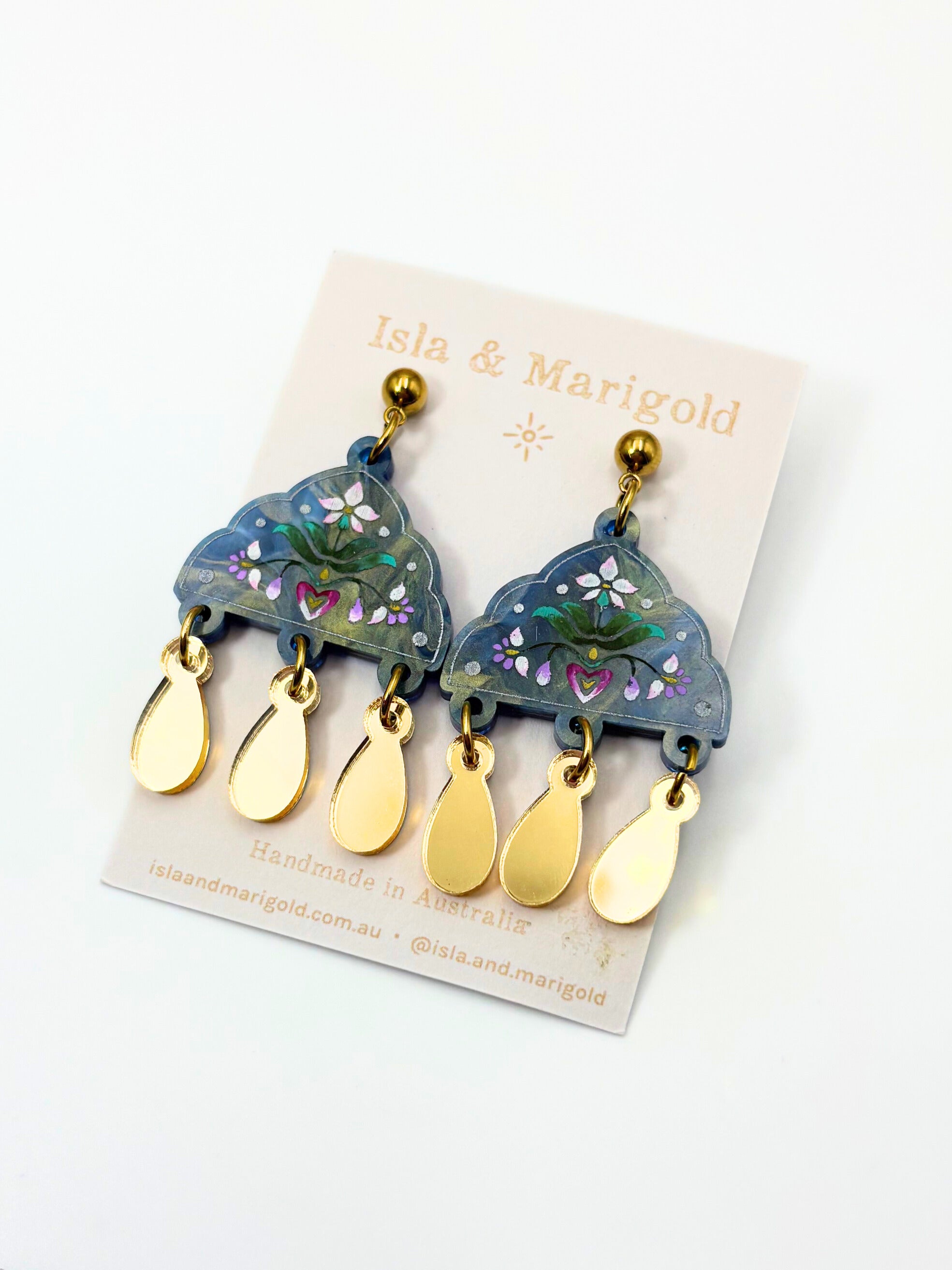 Pair of acrylic blue and gold earrings on a branded card with 'Isla & Marigold' branding.