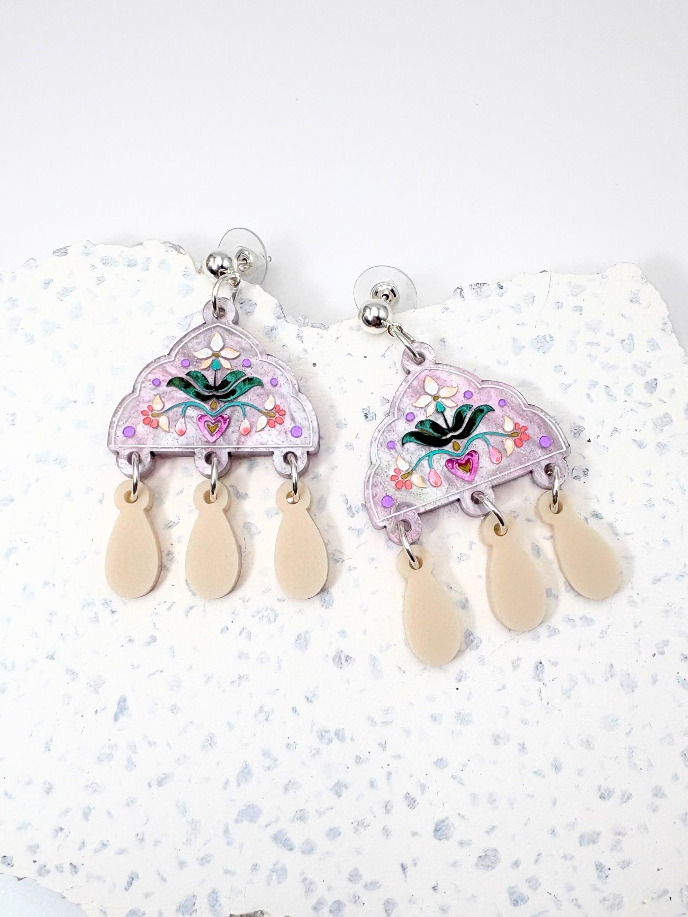 Pair of earrings with floral designs on a white background