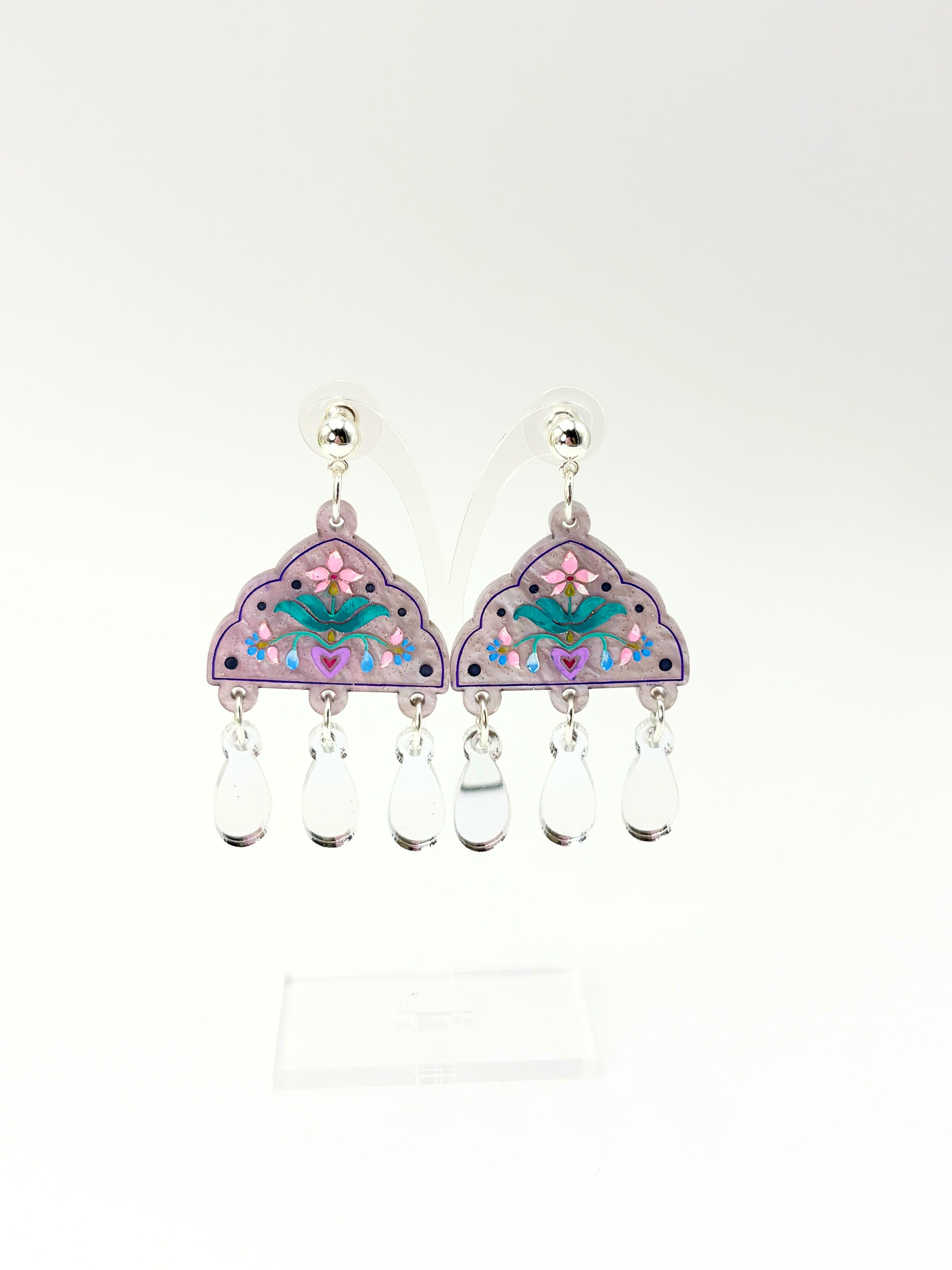 Pair of earrings with floral design and clear beads on a white background