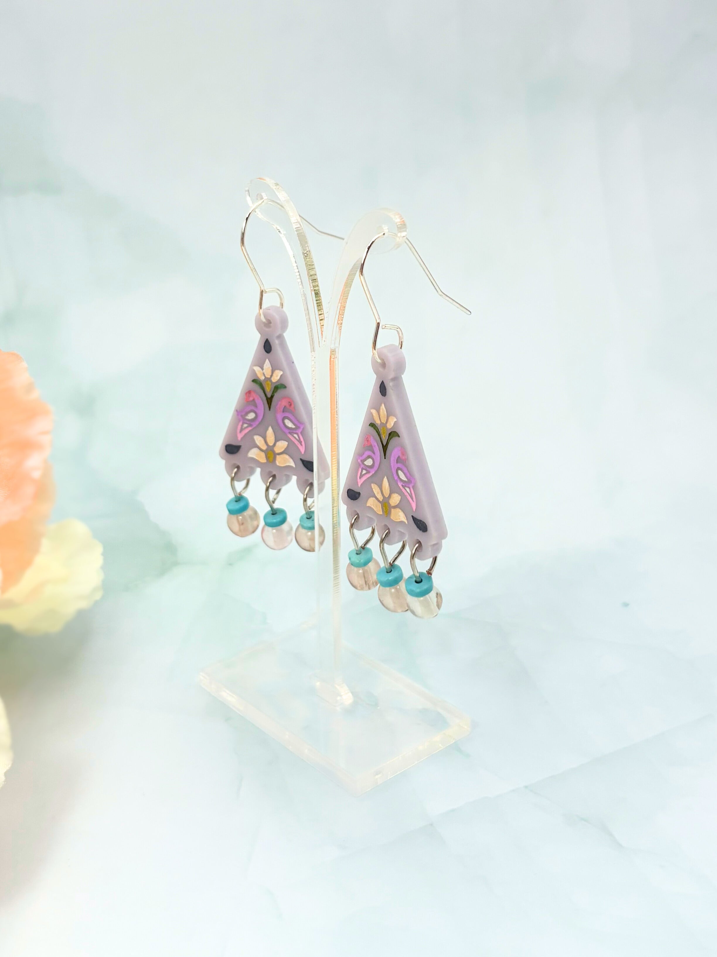 Colorful earrings with floral designs on a light blue background