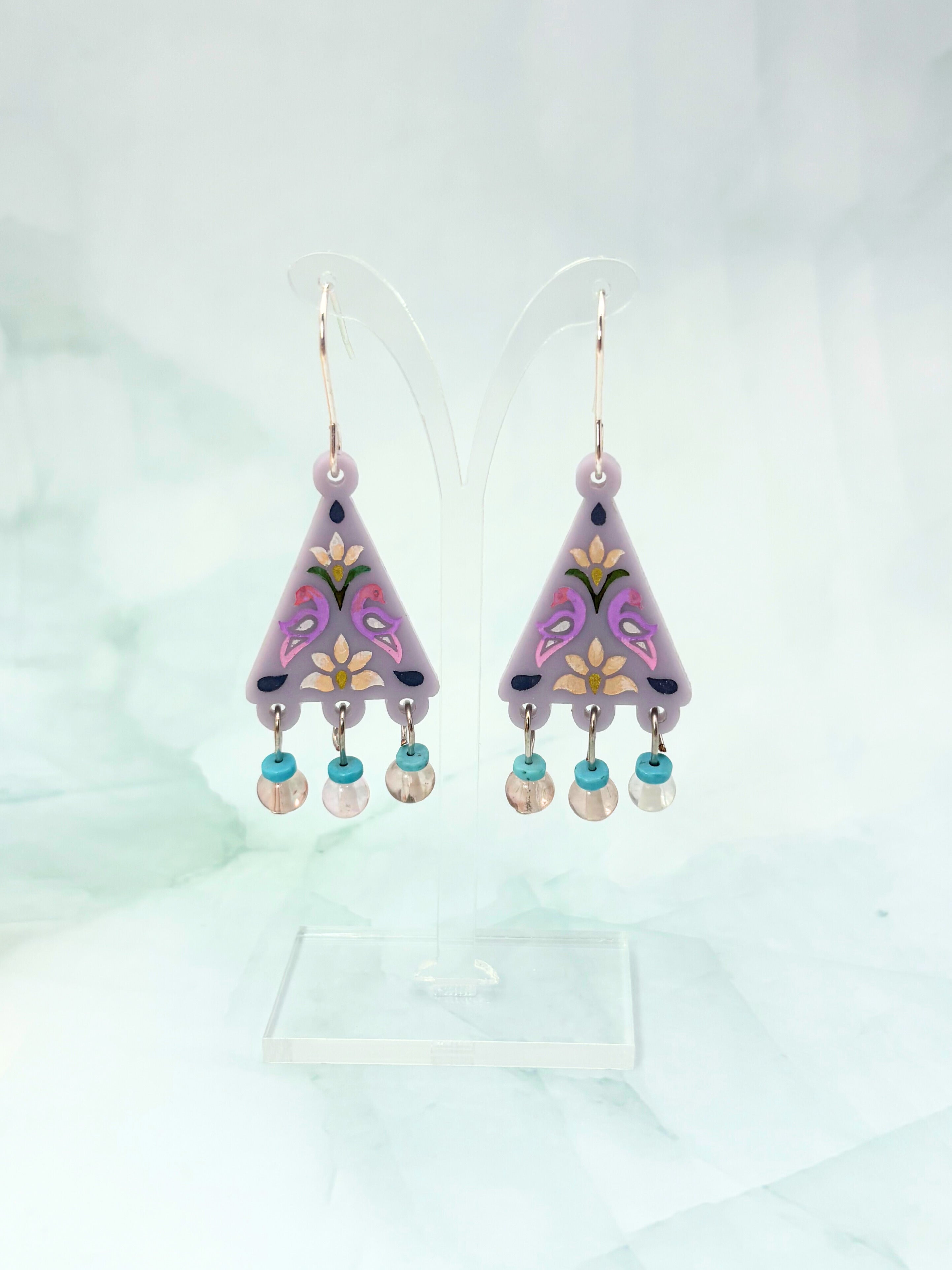 Pair of purple floral earrings with beads on a light gray background