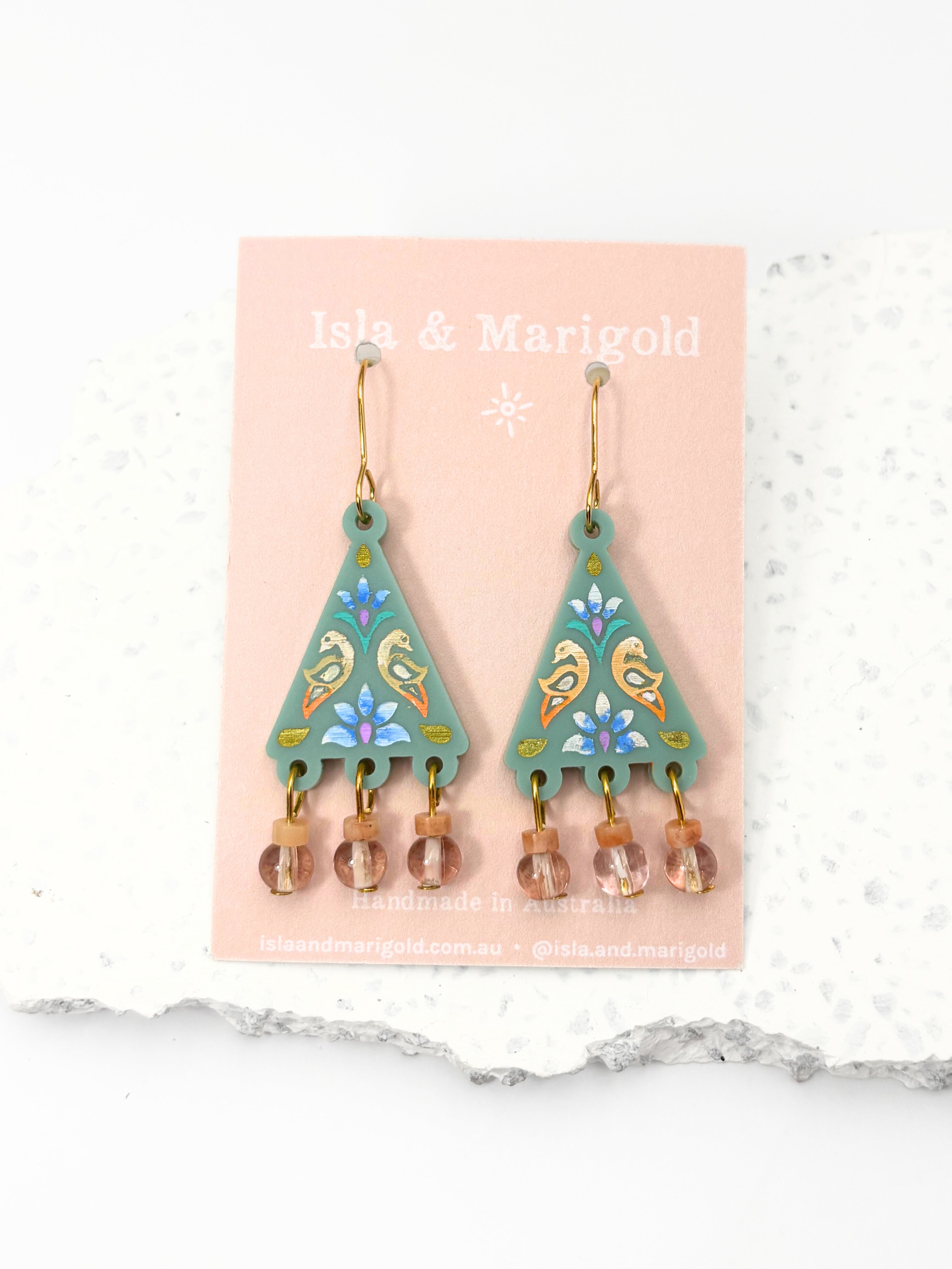 Pair of earrings on a pink card with 'Isla & Marigold' branding against a white background.