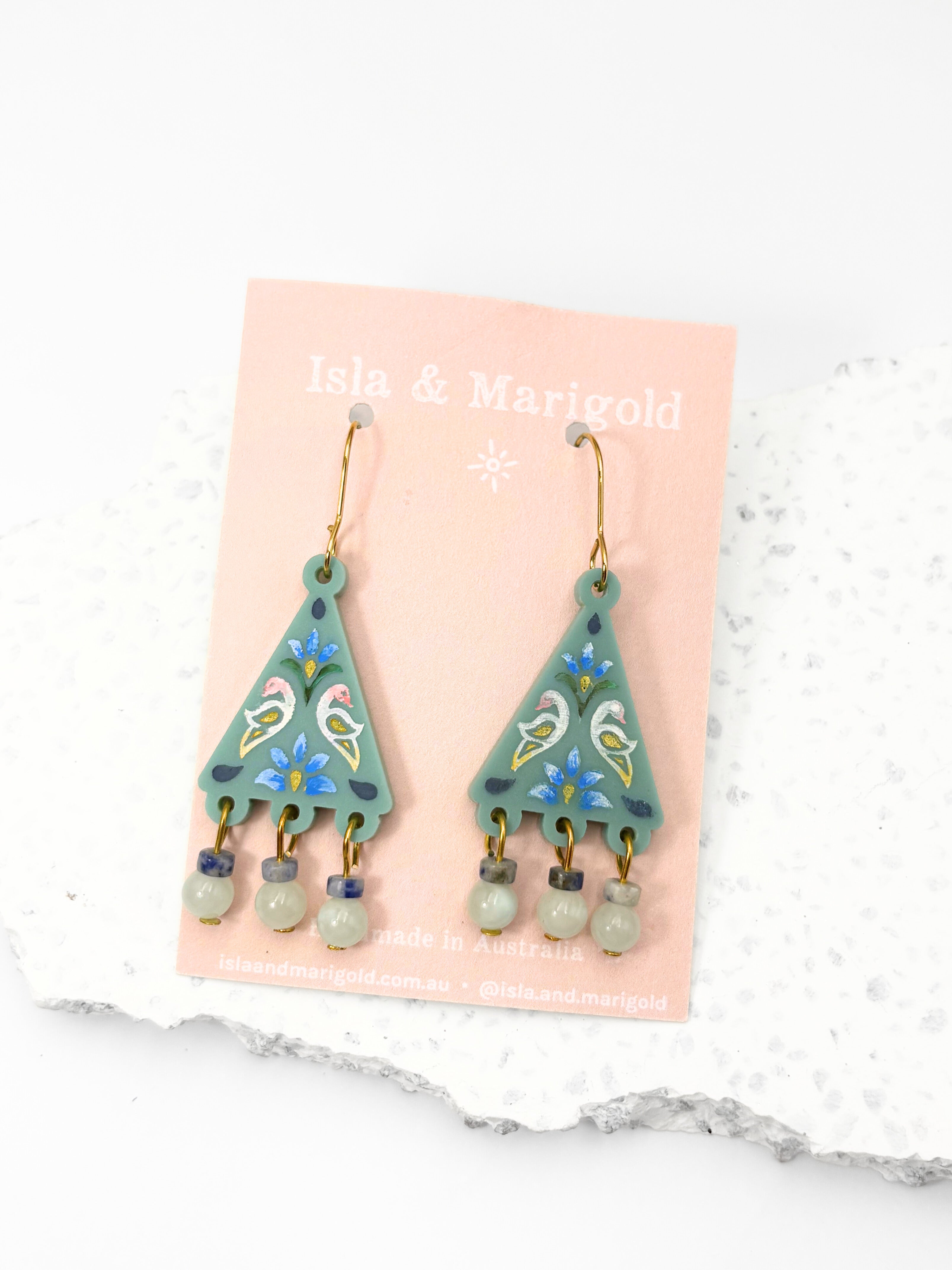Green earrings with floral designs on a pink card with 'Isla & Margold' branding, against a white background.