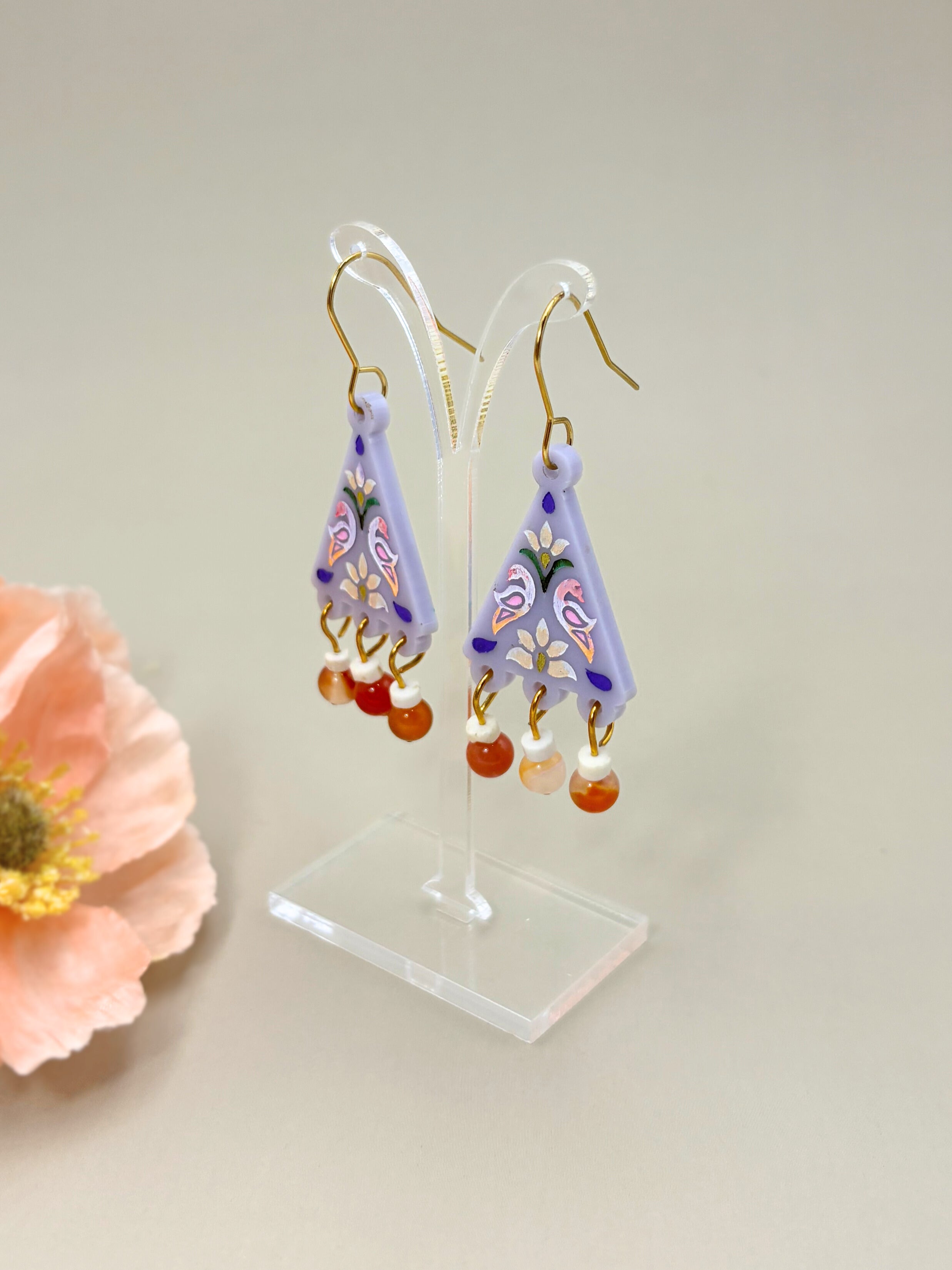 Pair of colorful earrings on a clear stand with a light background