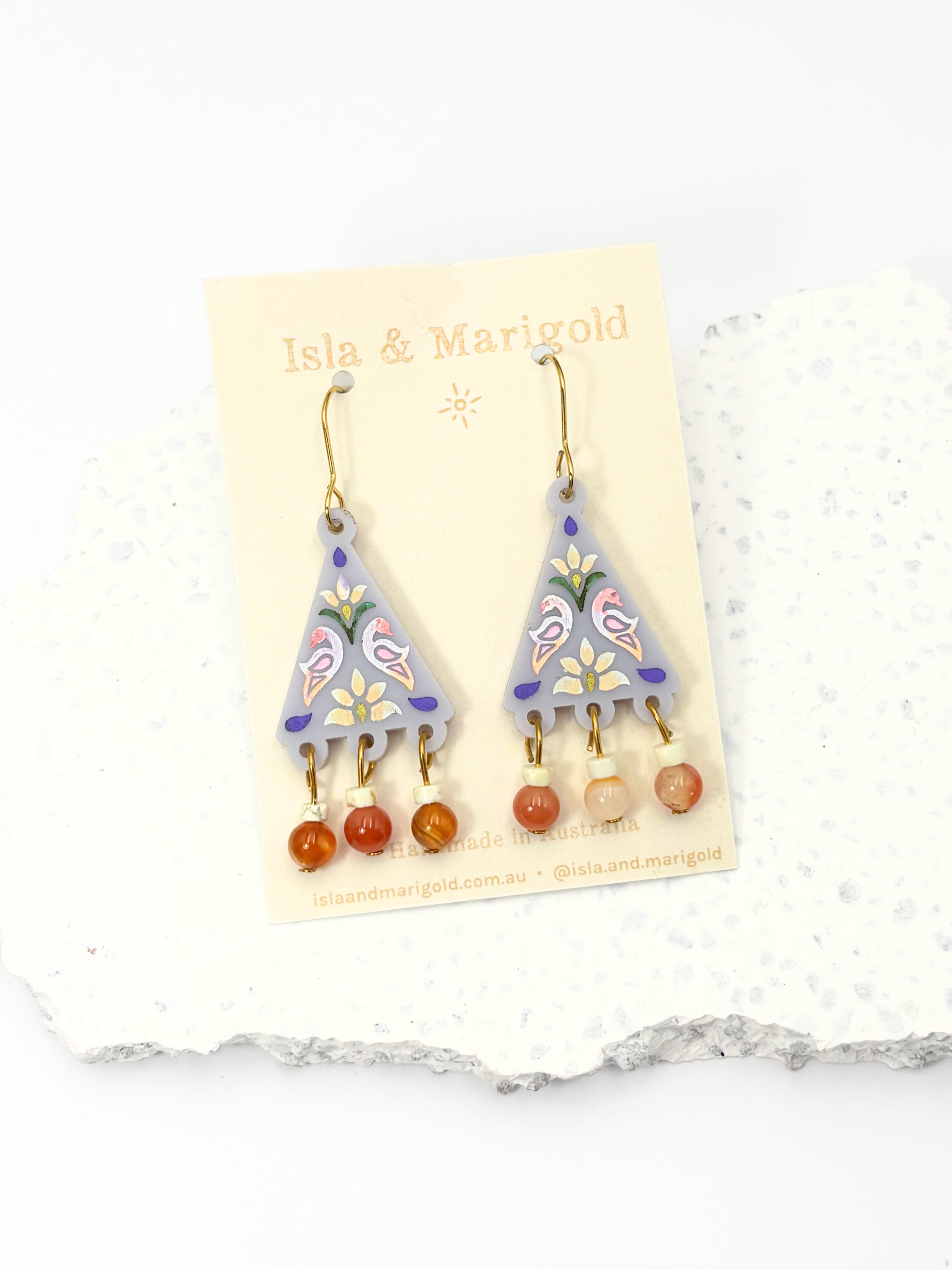 Pair of earrings on a branded card with a white background