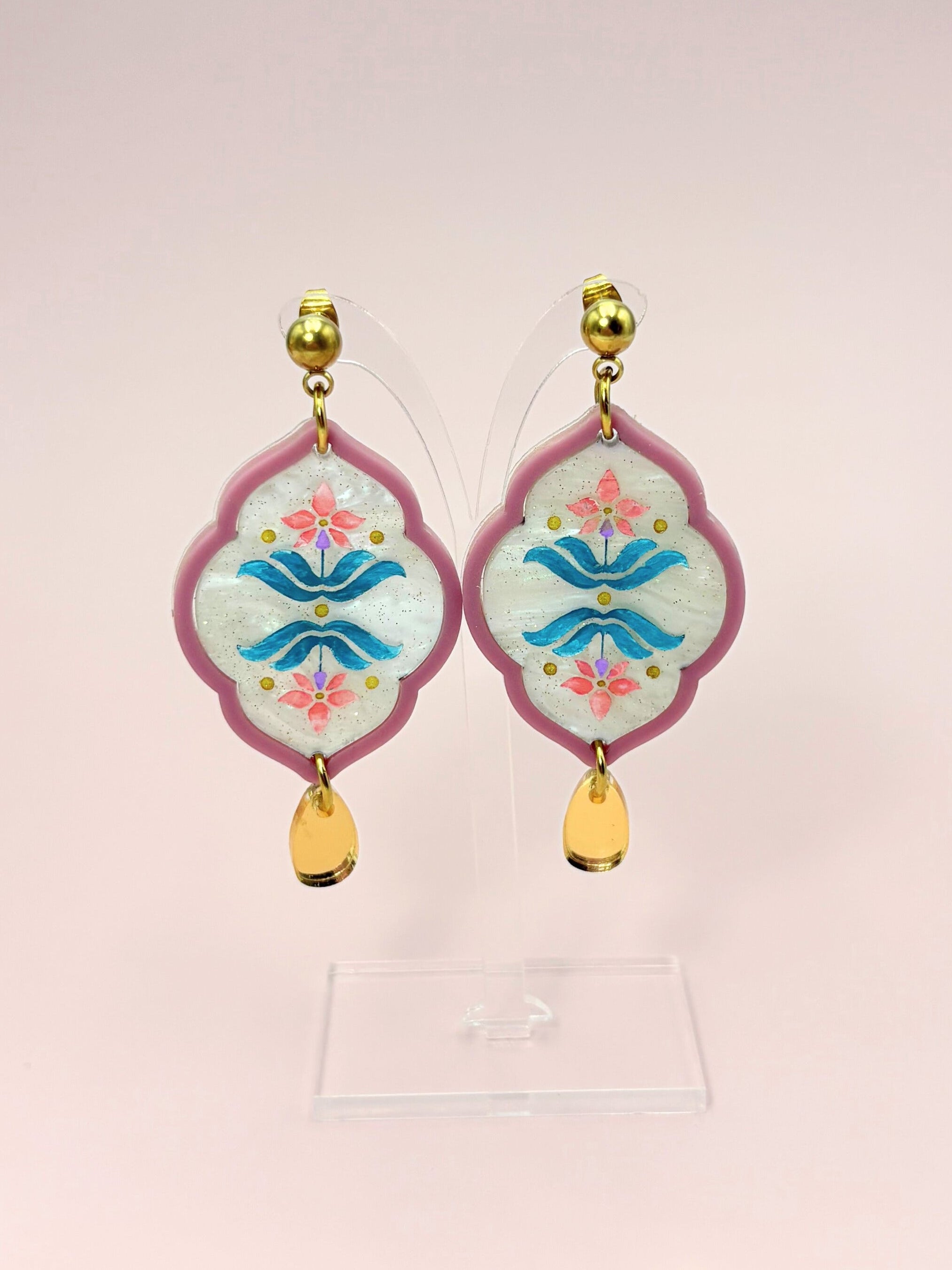 Decorative earrings with floral design on a pink background