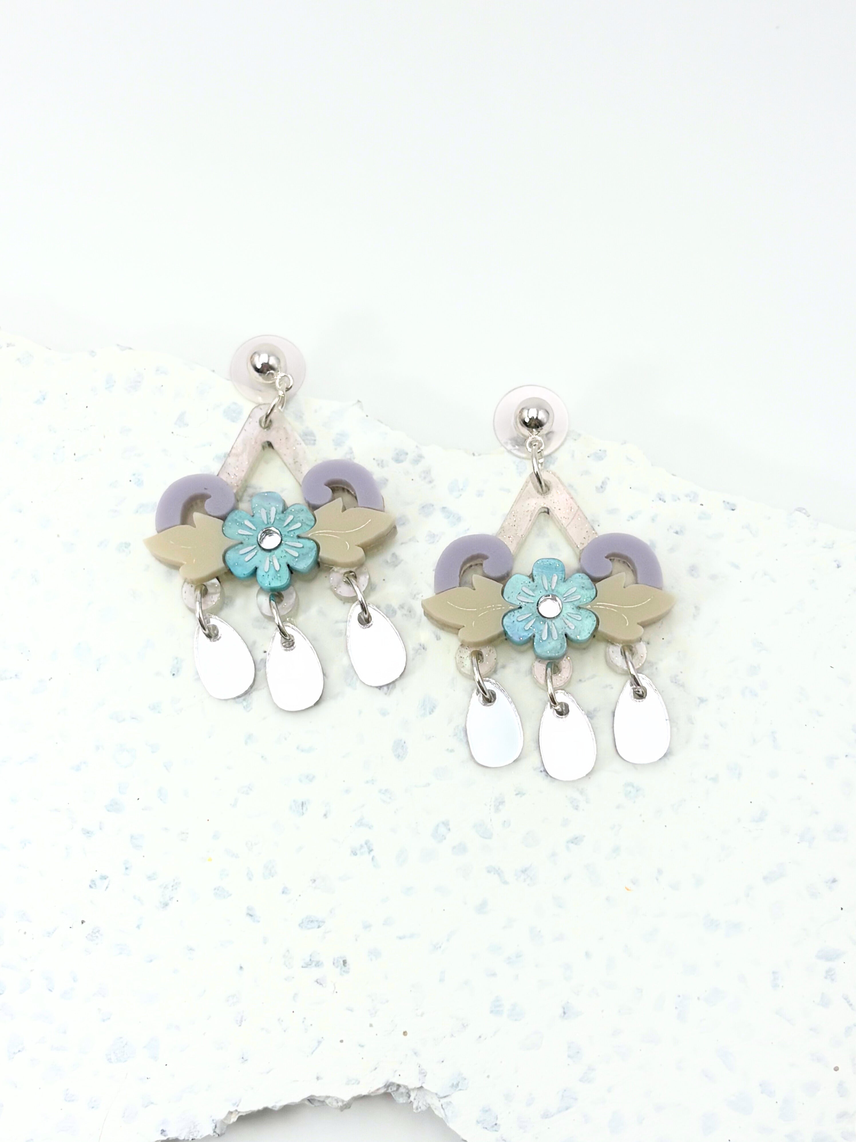Pair of earrings with floral and arrow designs on a light background