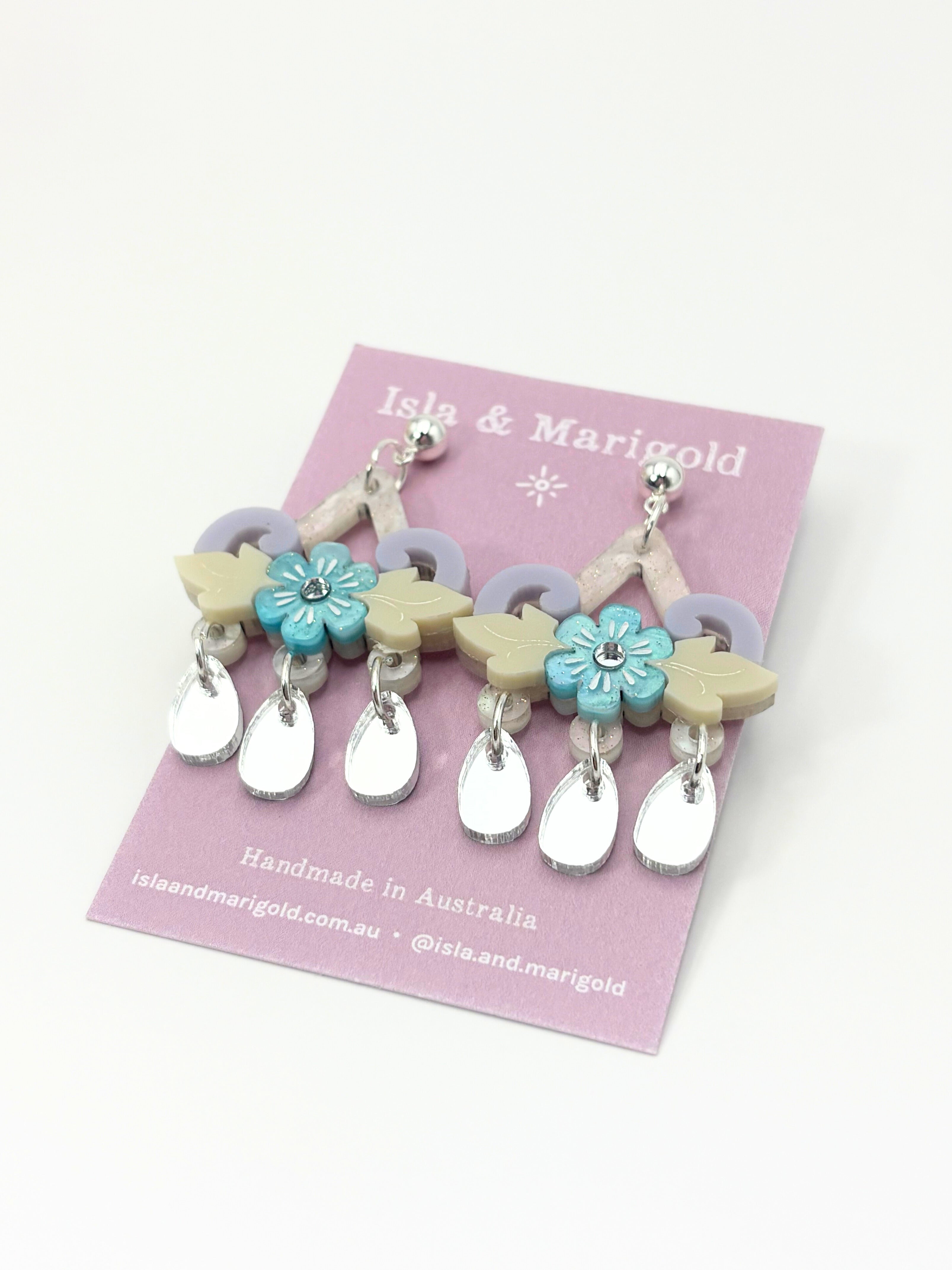Colorful earrings on a pink card with 'Isla & Marigold' branding.