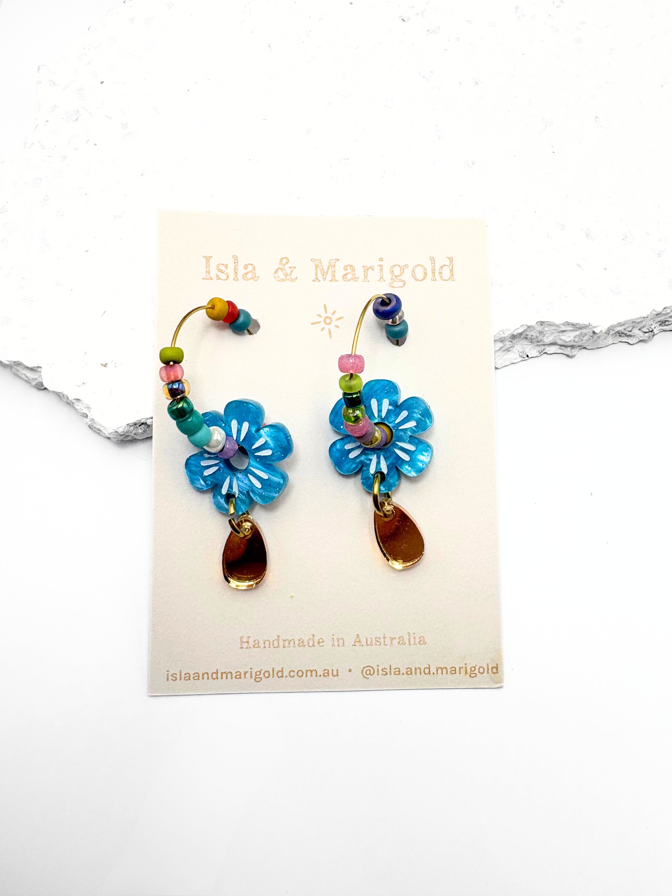Colorful flower-shaped earrings on a branded card with 'Isla & Marigold' branding.