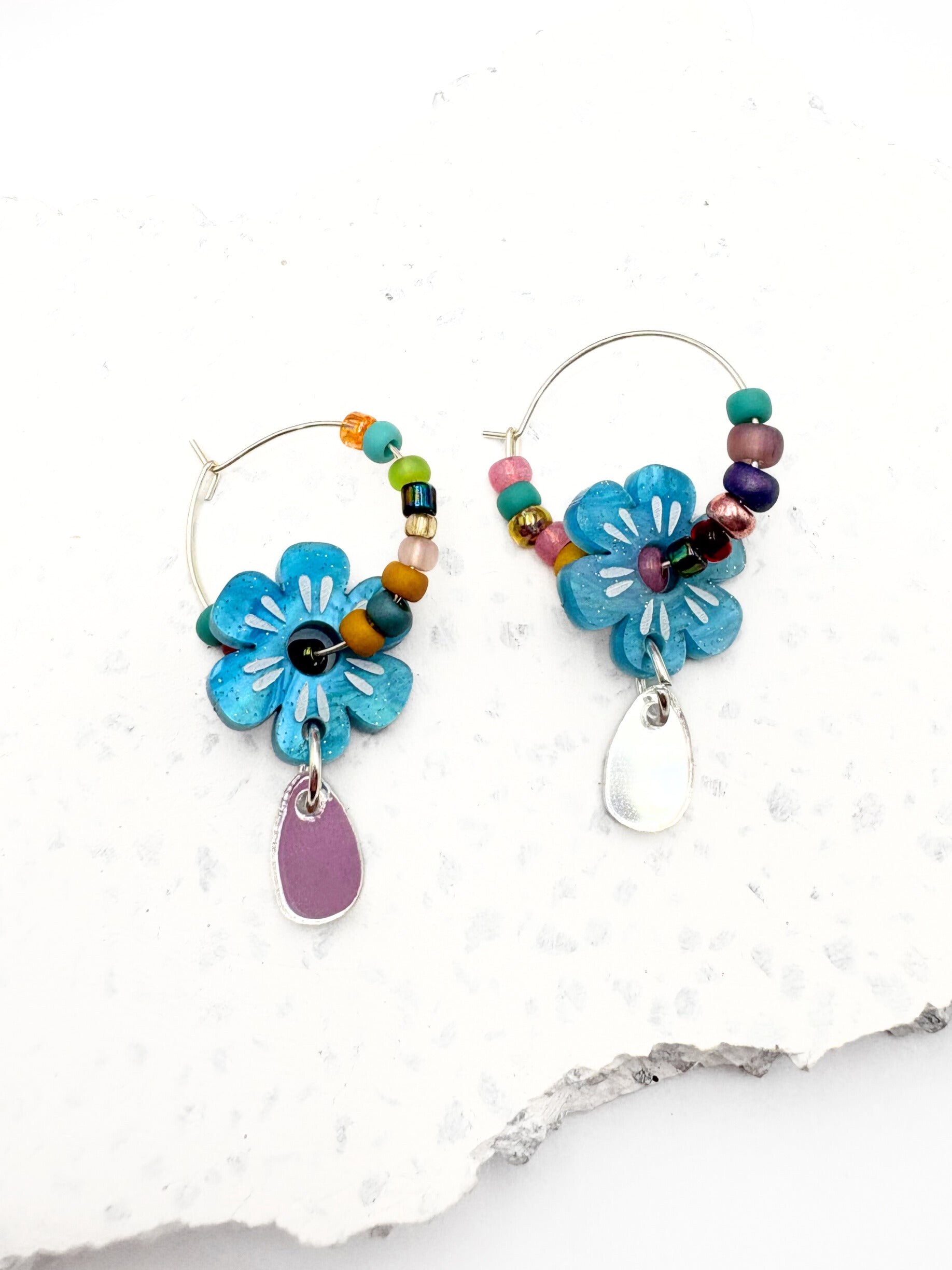Colorful flower-shaped earrings with beads on a white background