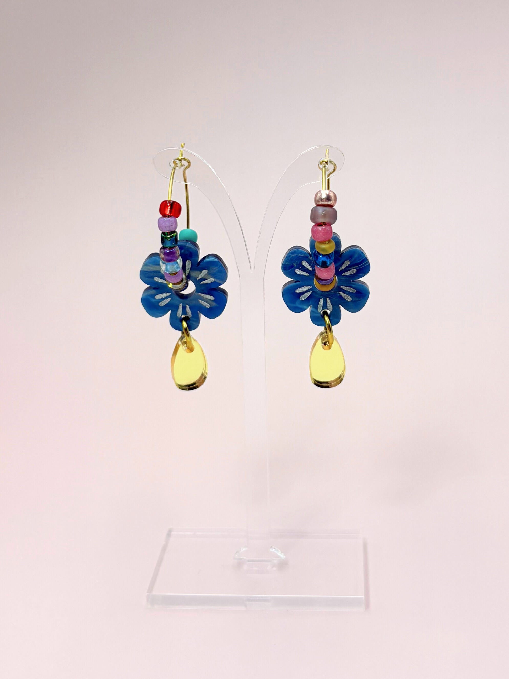 Colorful flower-shaped earrings on a pink background