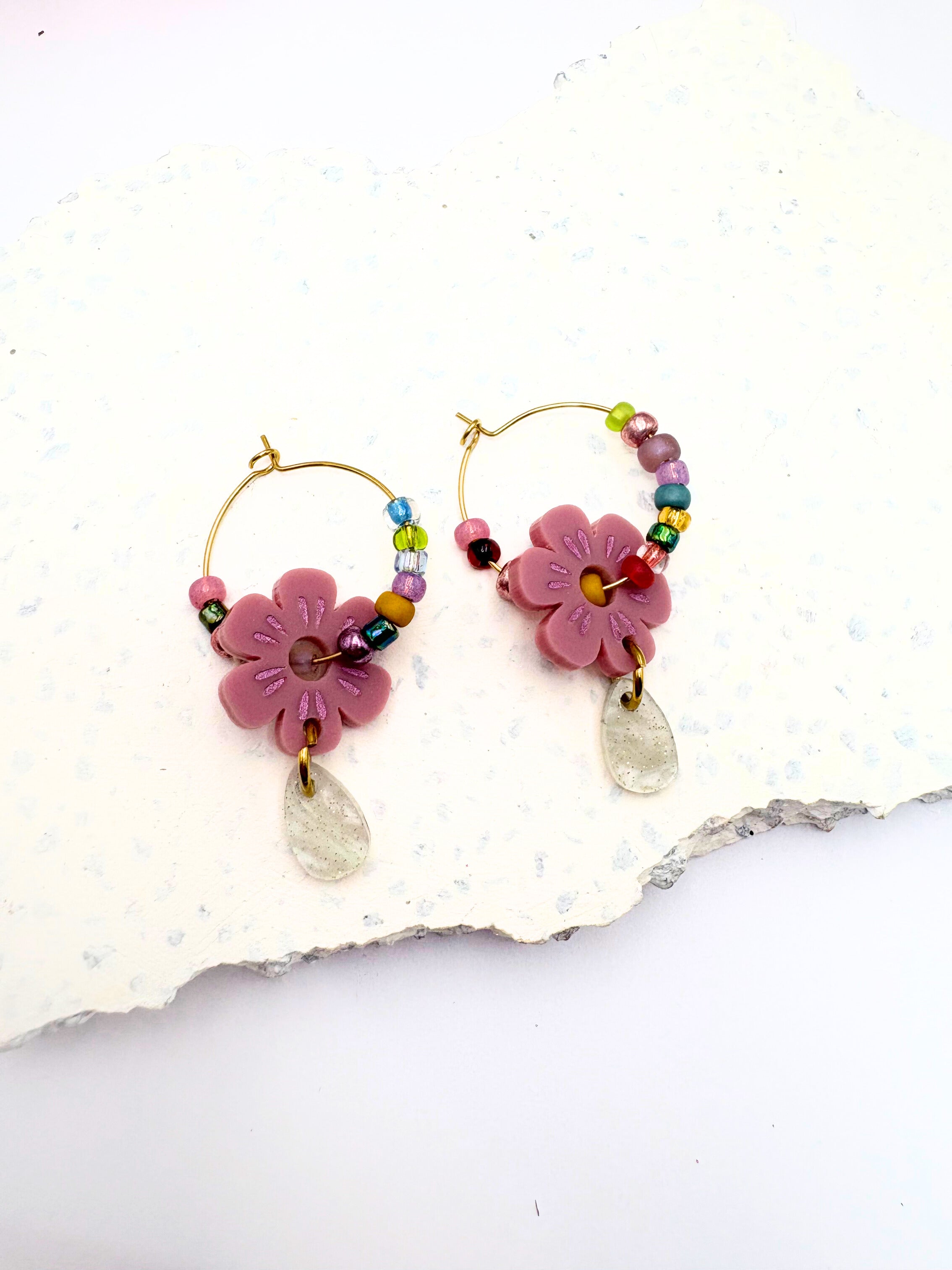 Pair of floral earrings with colorful beads on a textured white surface
