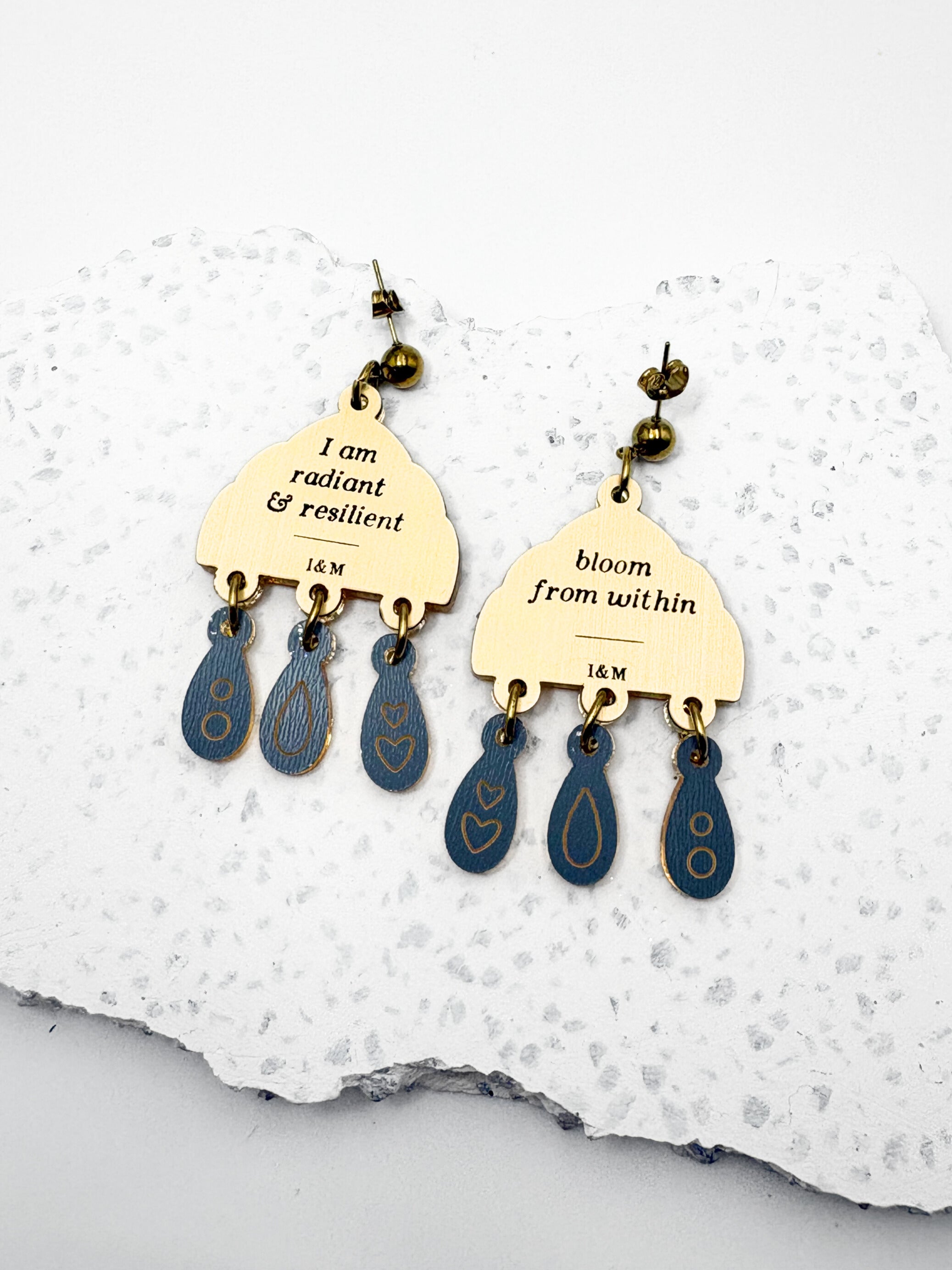 Pair of earrings with motivational phrases on a white stone background