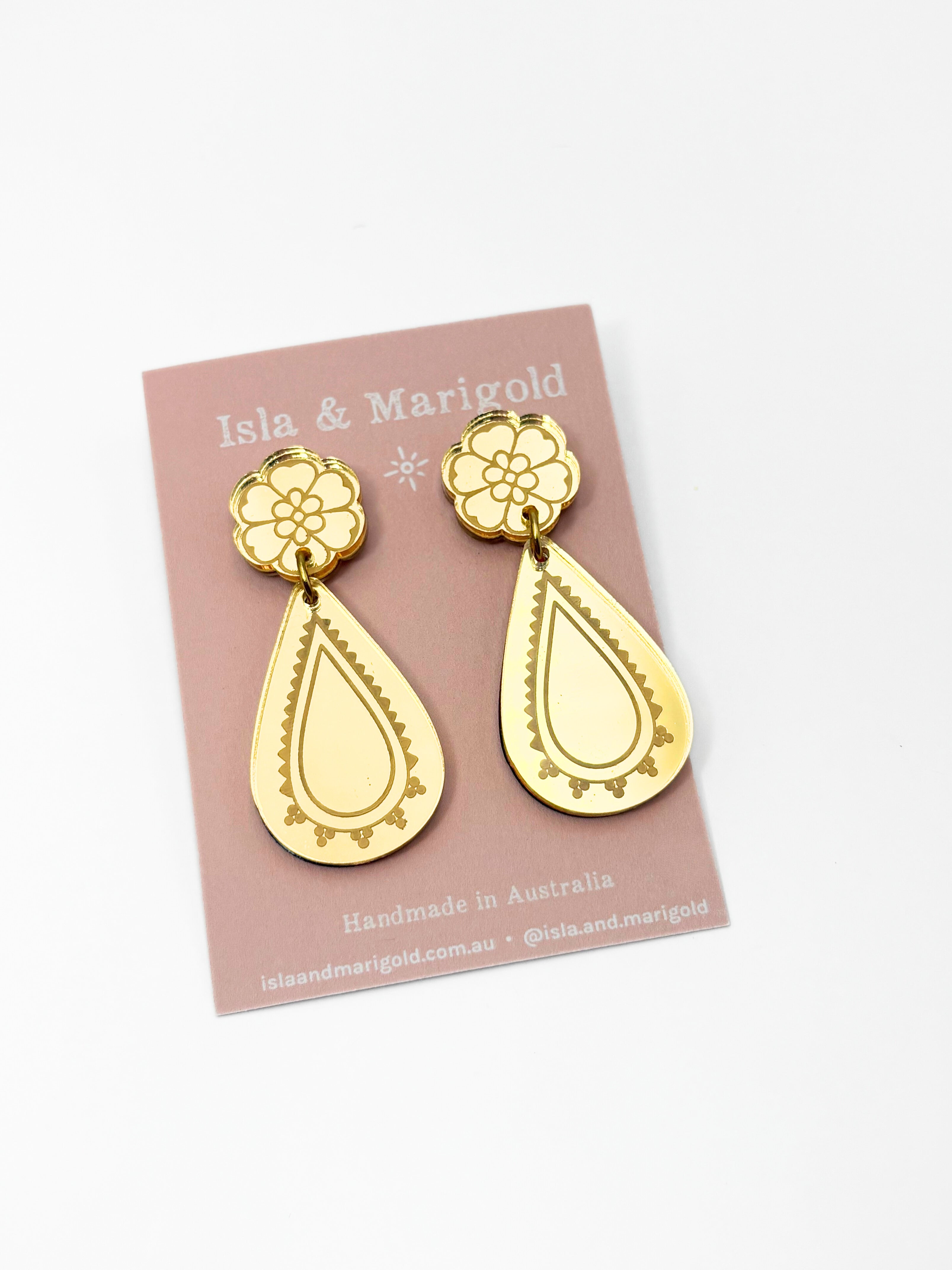Gold earrings on a pink card with 'Isla & Marigold' branding.
