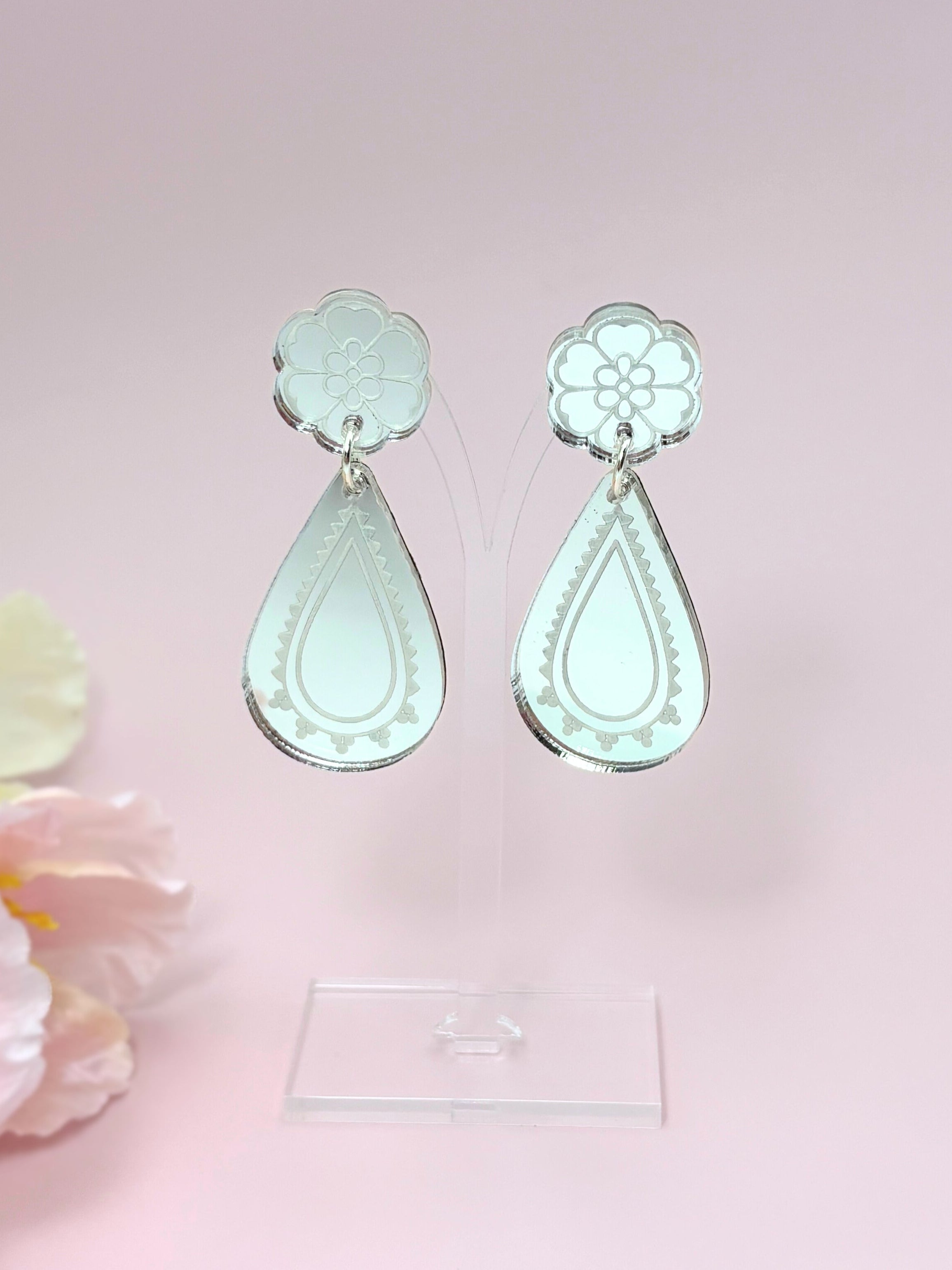 Pair of silver teardrop-shaped earrings on a pink background