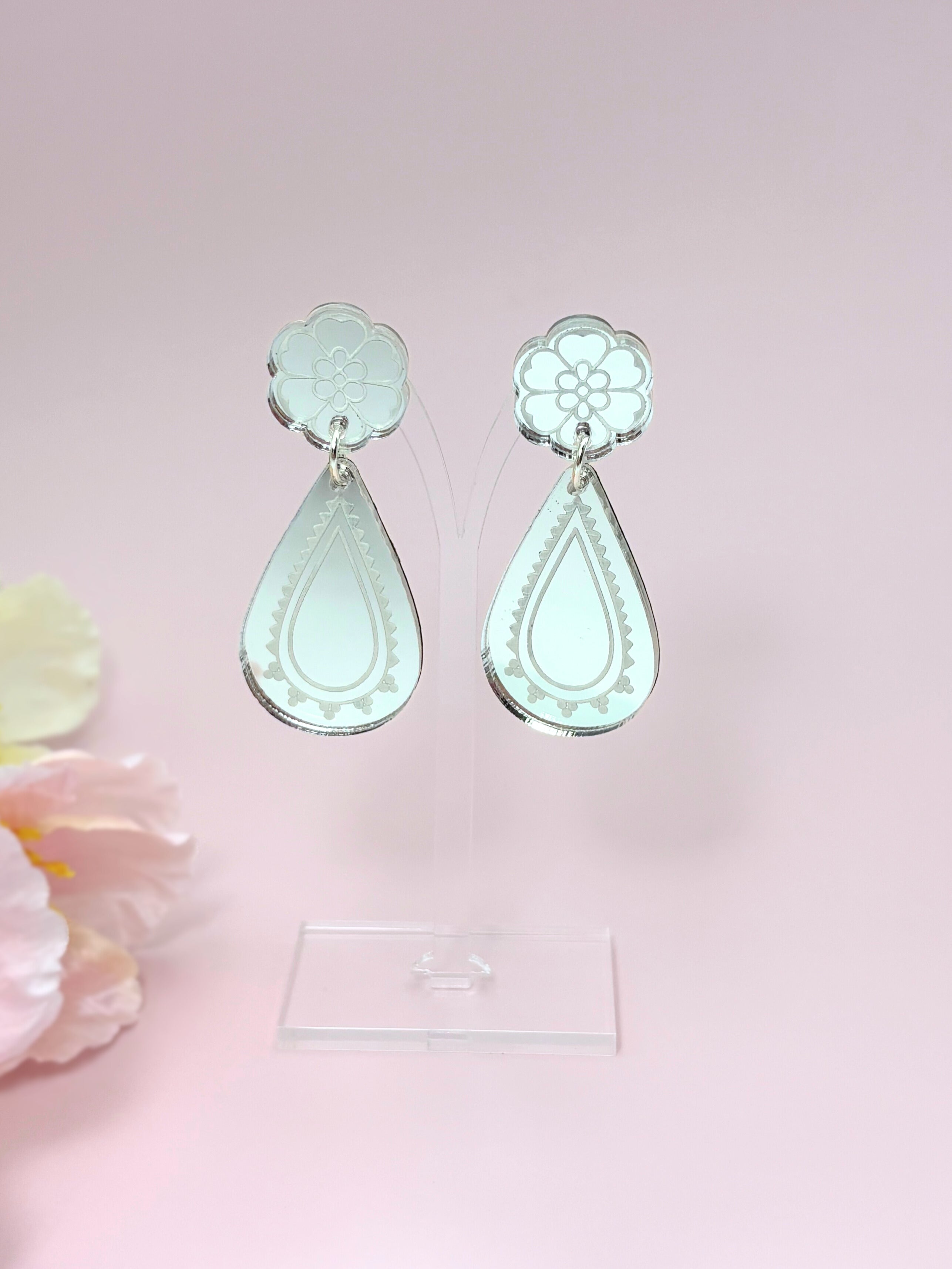 Pair of silver teardrop-shaped earrings on a pink background