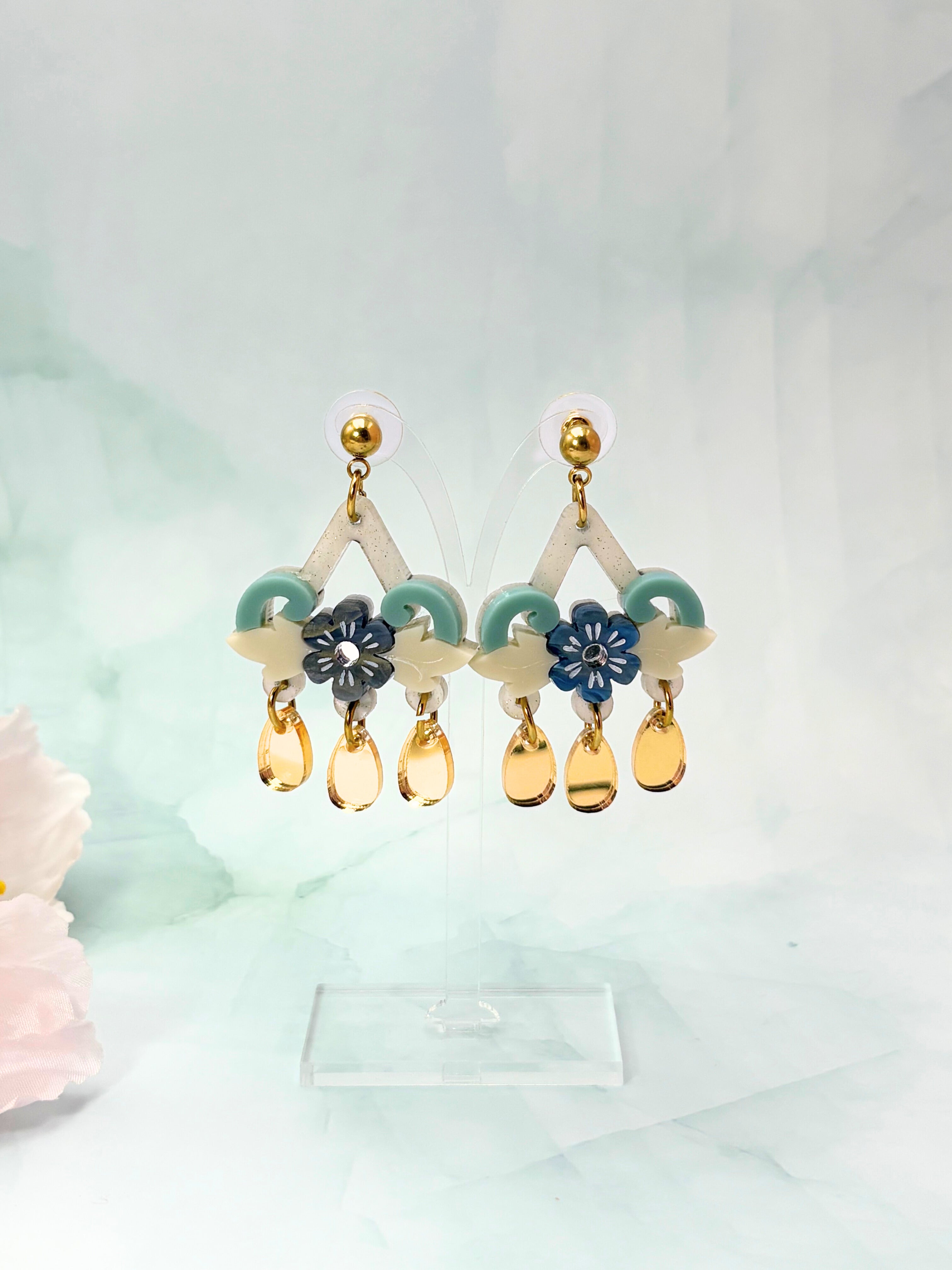 Colorful earrings with floral and teardrop designs on a light background