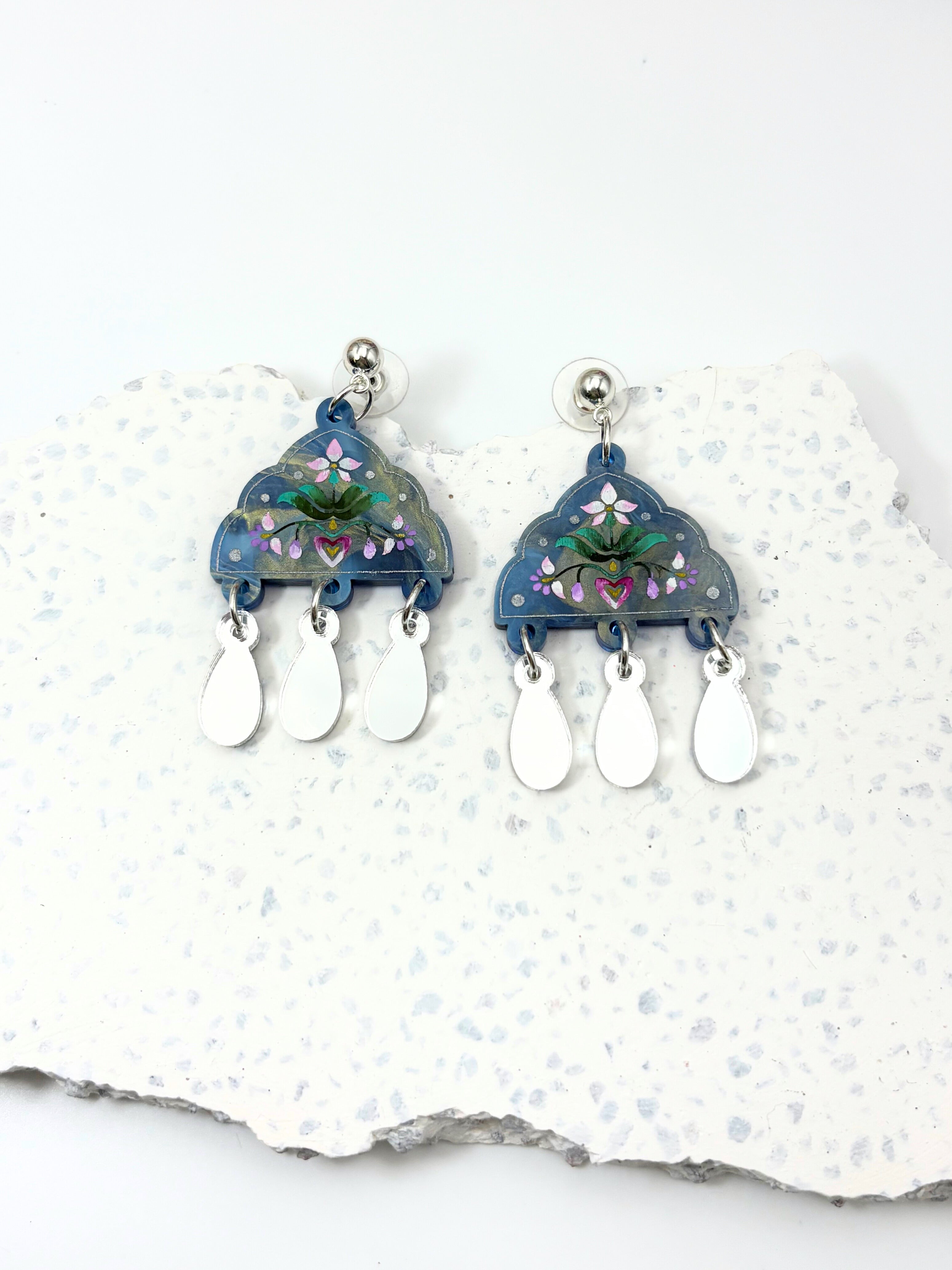 Pair of blue floral earrings on a white stone background