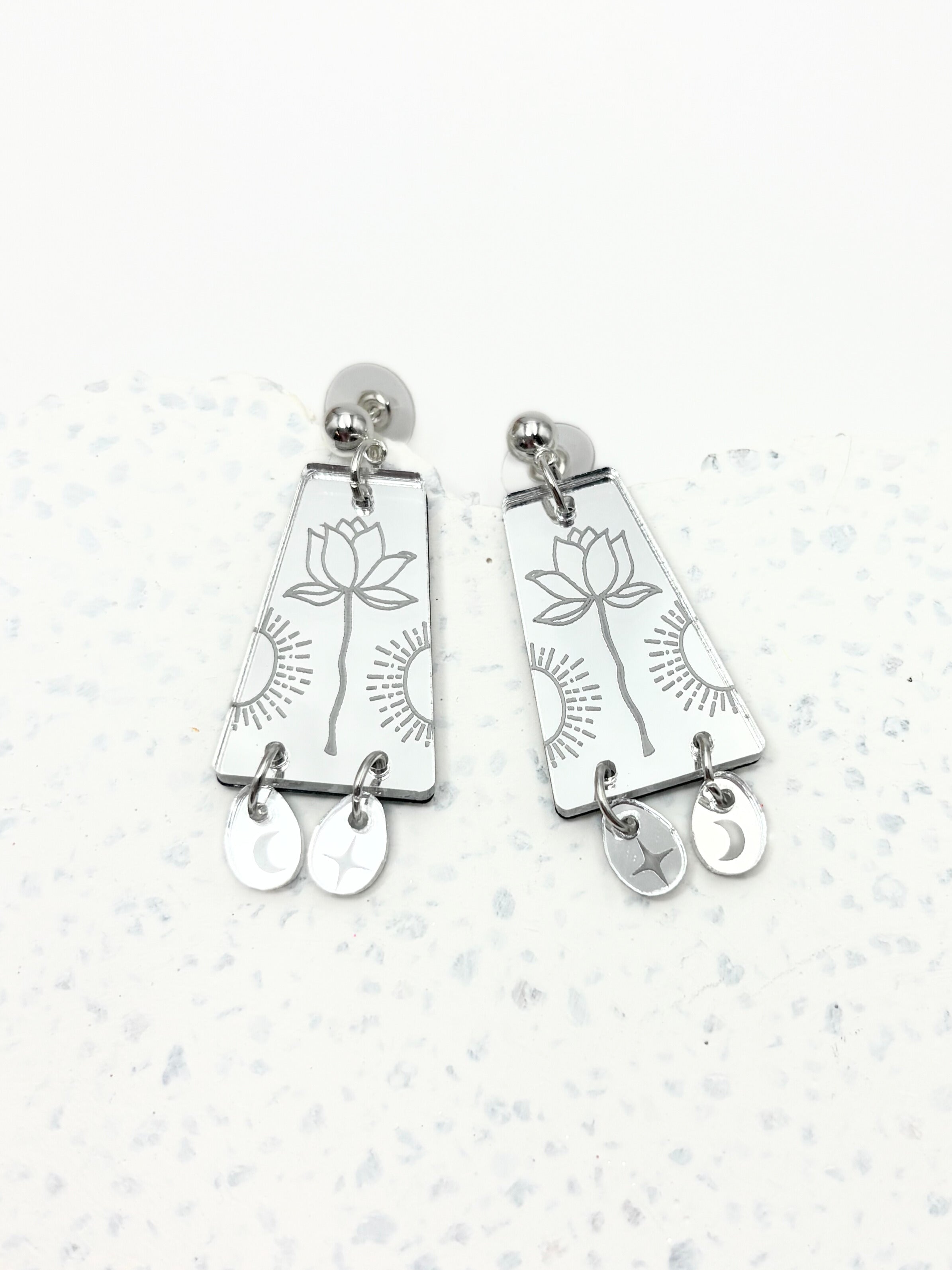Pair of silver earrings with floral design on a light gray background