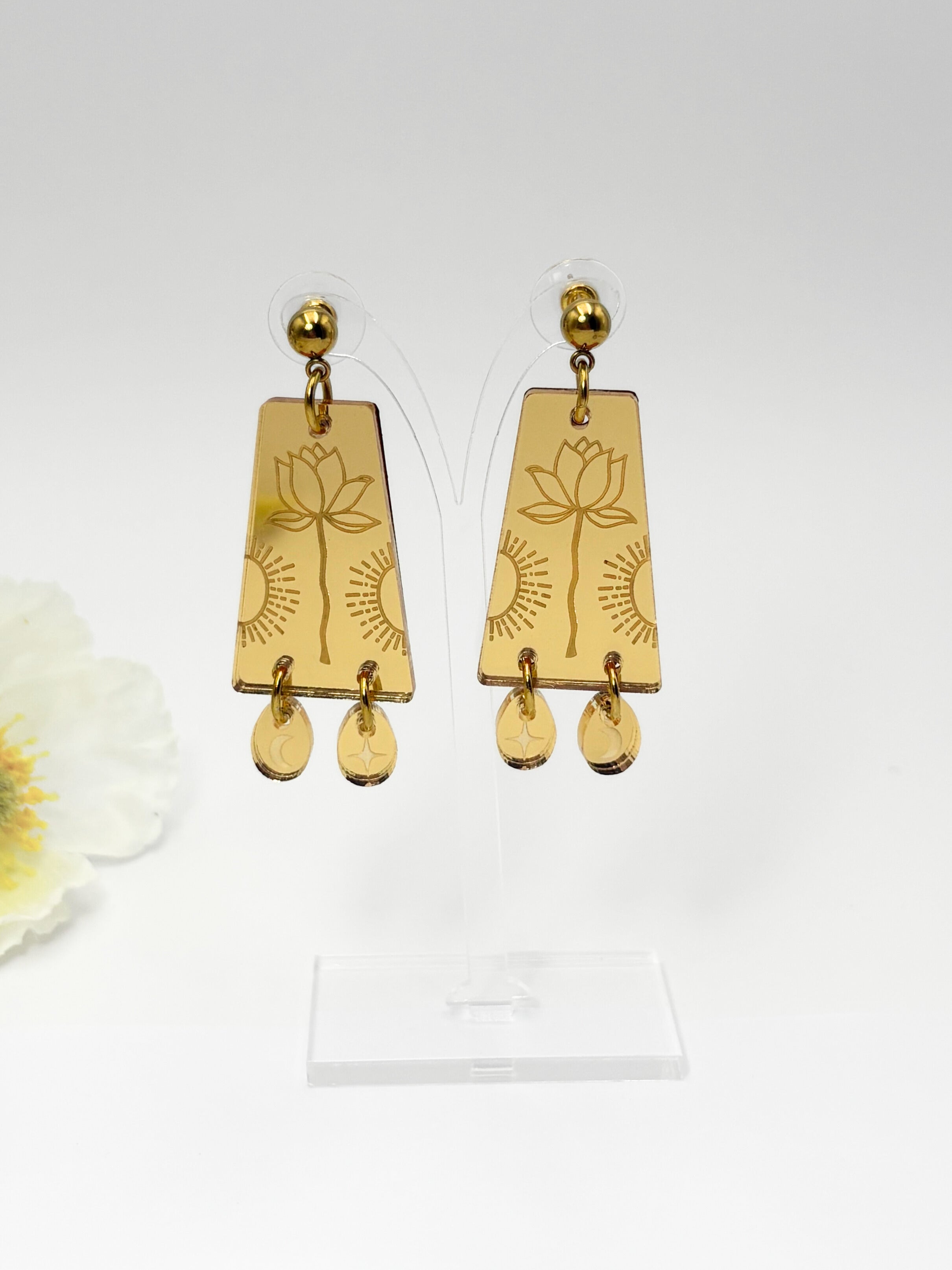 Gold earrings with lotus designs on a white background