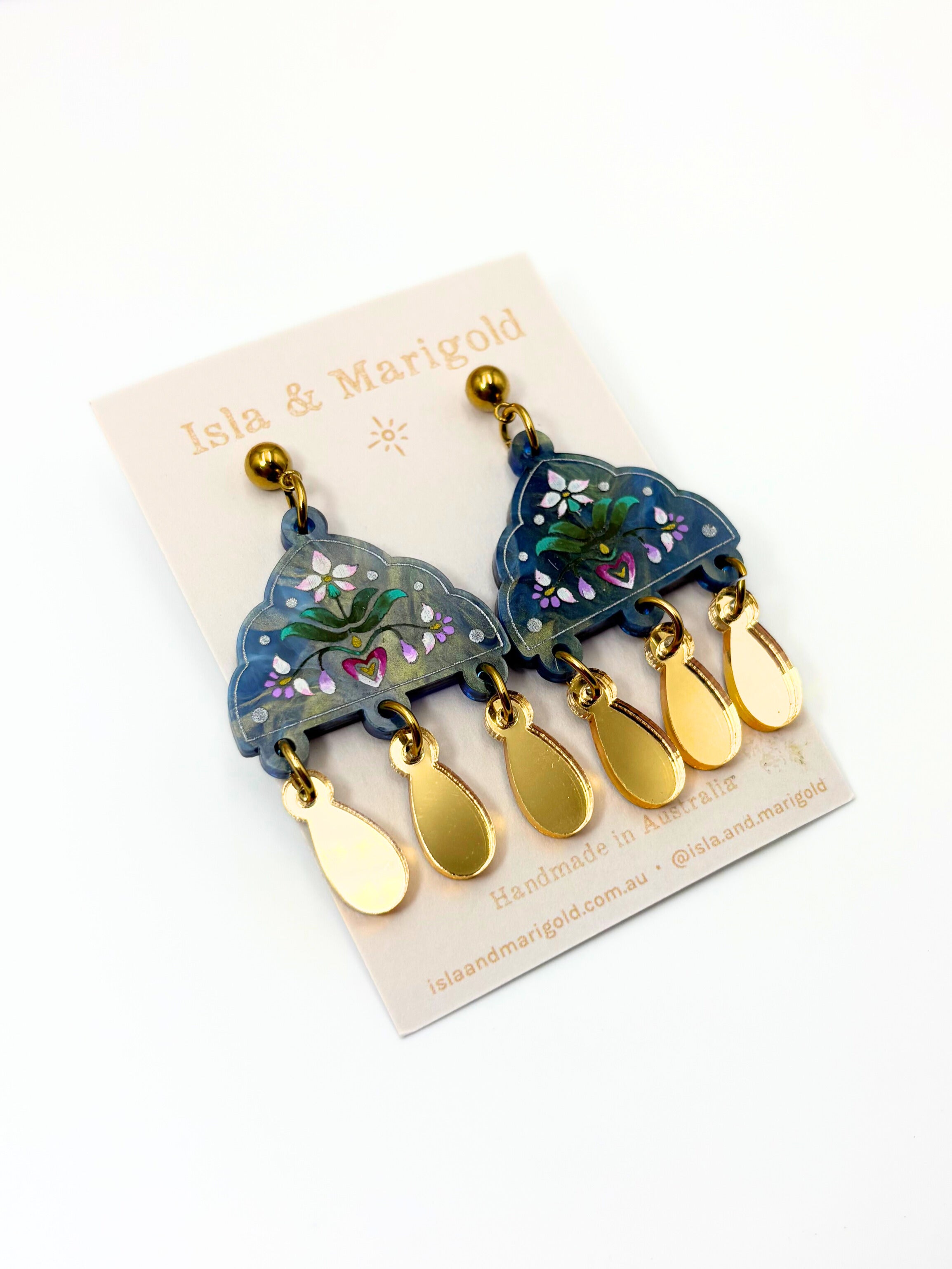 Pair of earrings with gold and blue design on a branded card
