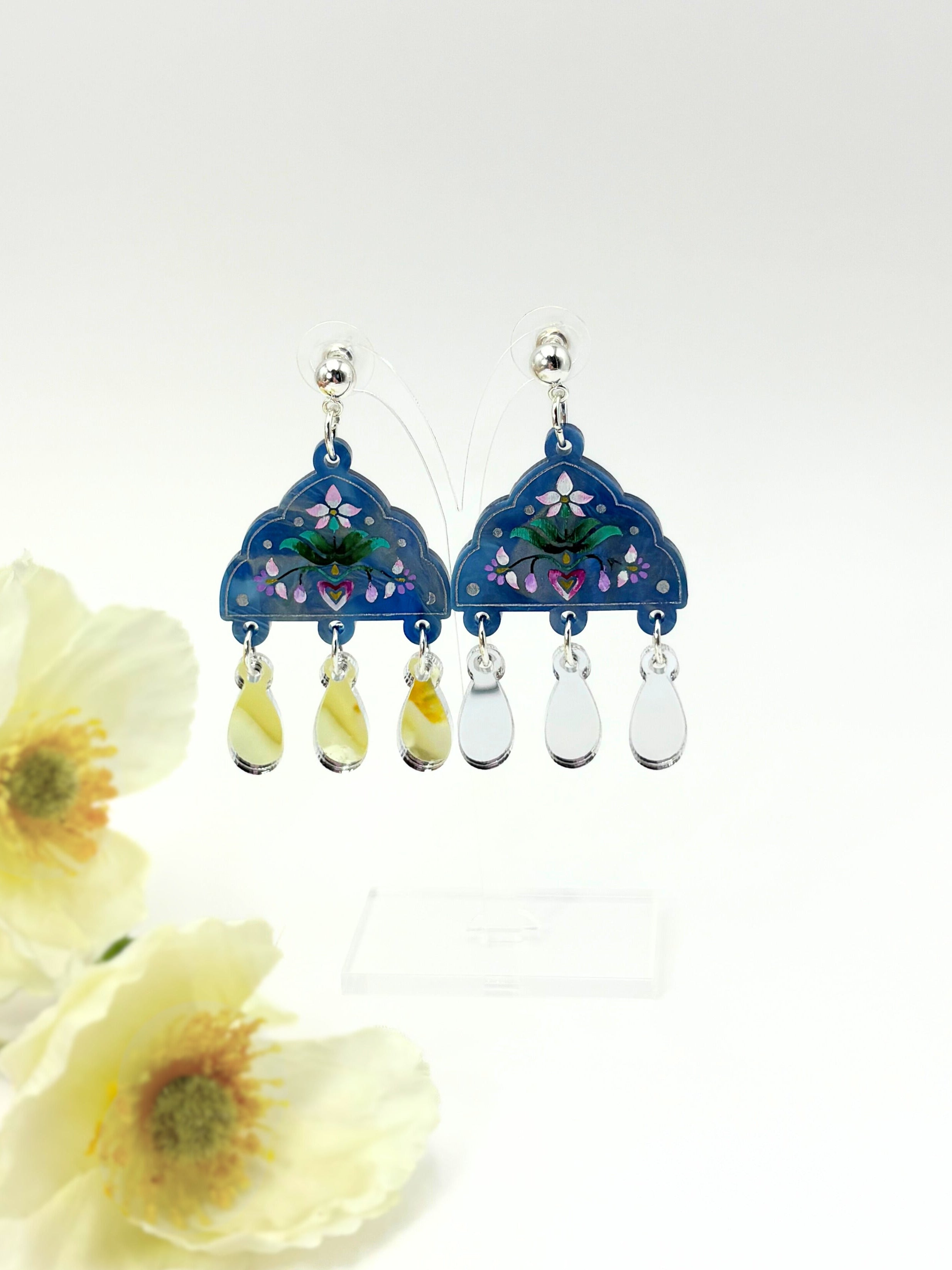 Blue floral acrylic earrings with teardrop-shaped charms on a white background