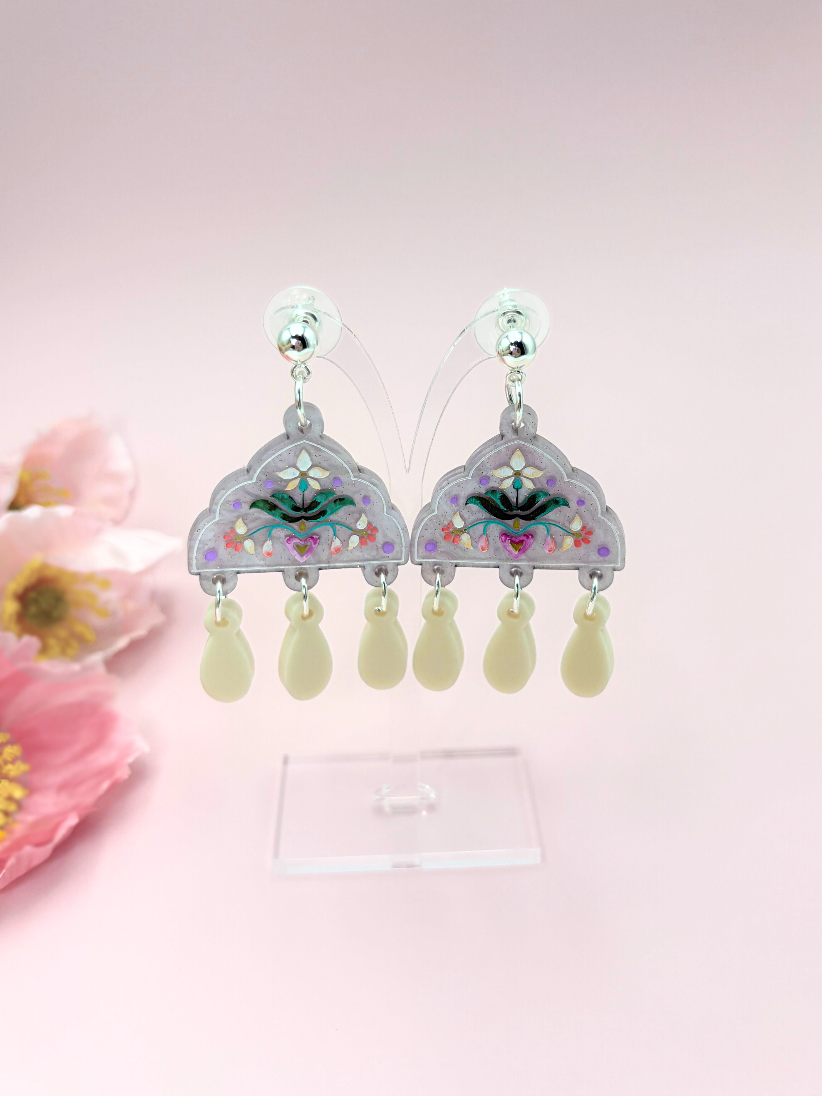 Decorative acrylic earrings with floral design on a pink background