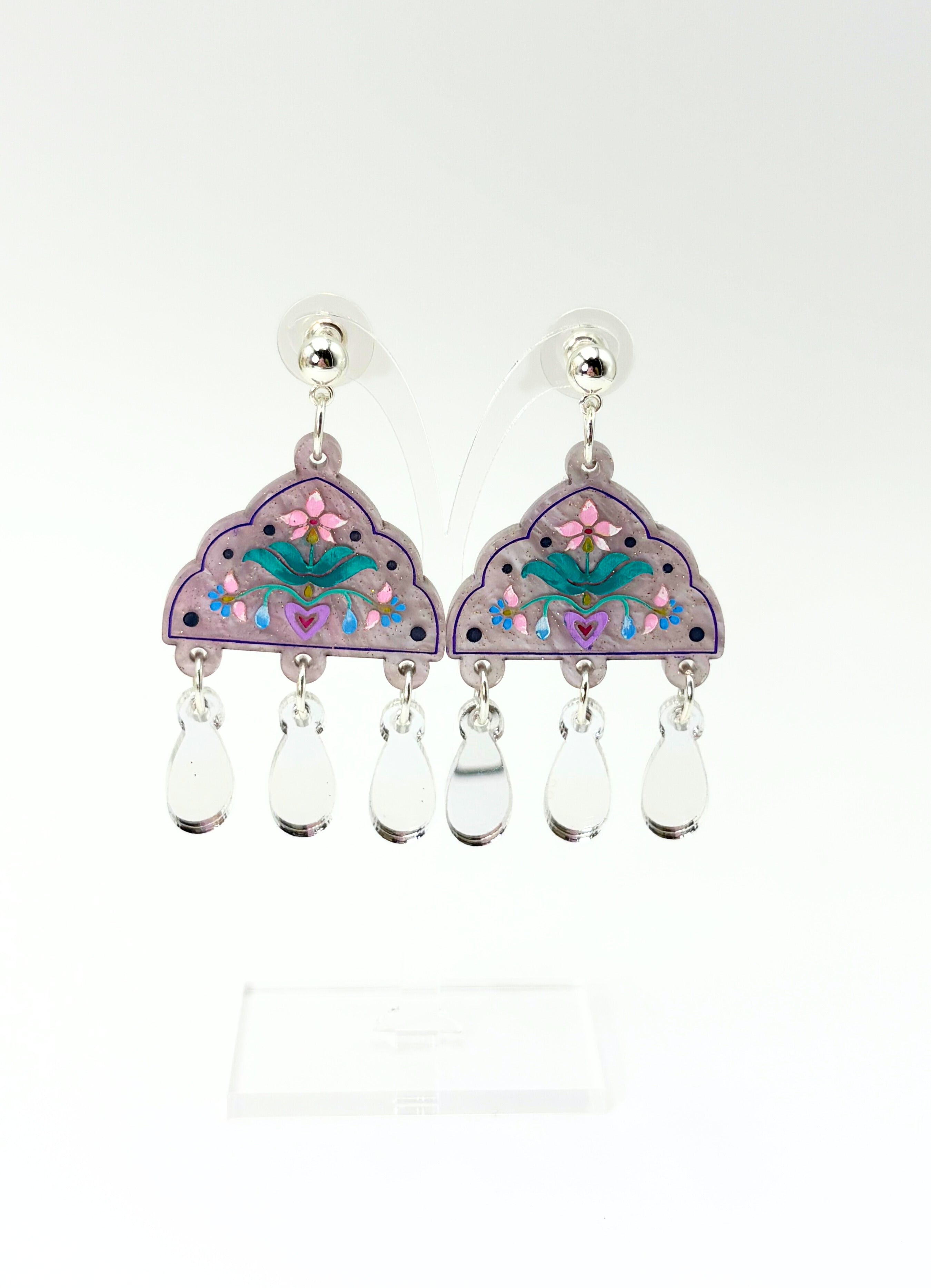 Pair of earrings with floral design and clear beads on a white background