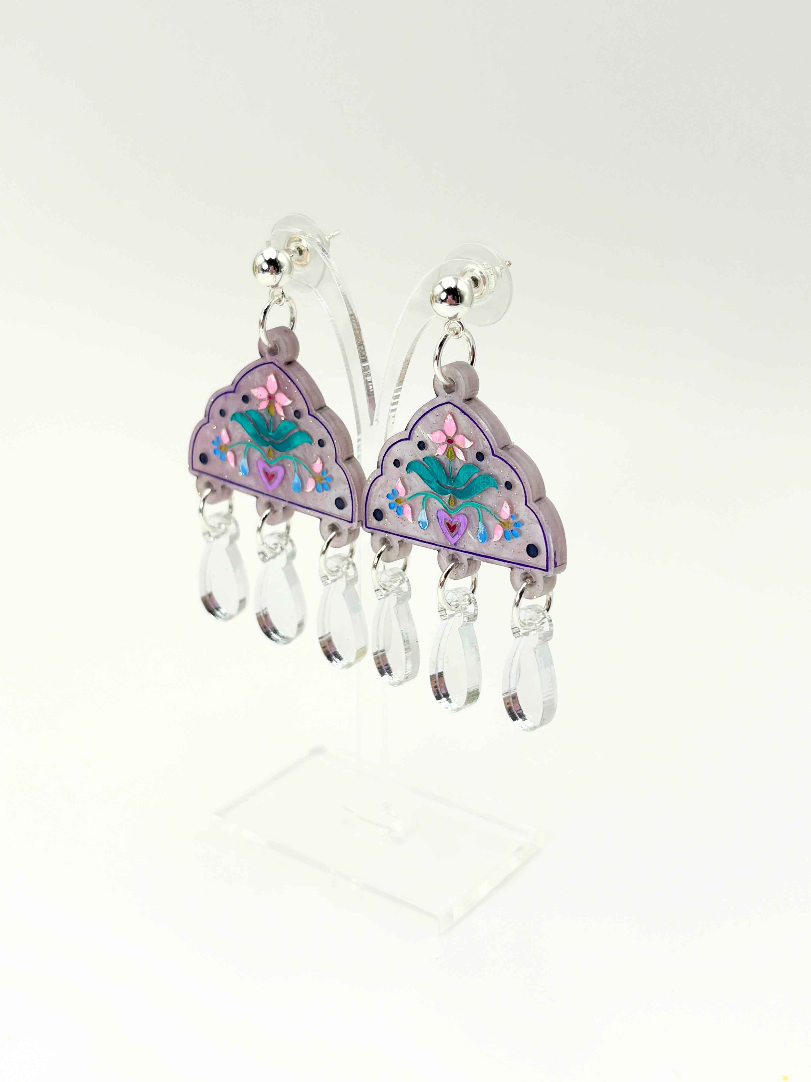 Pair of earrings with floral design and clear beads on a white background