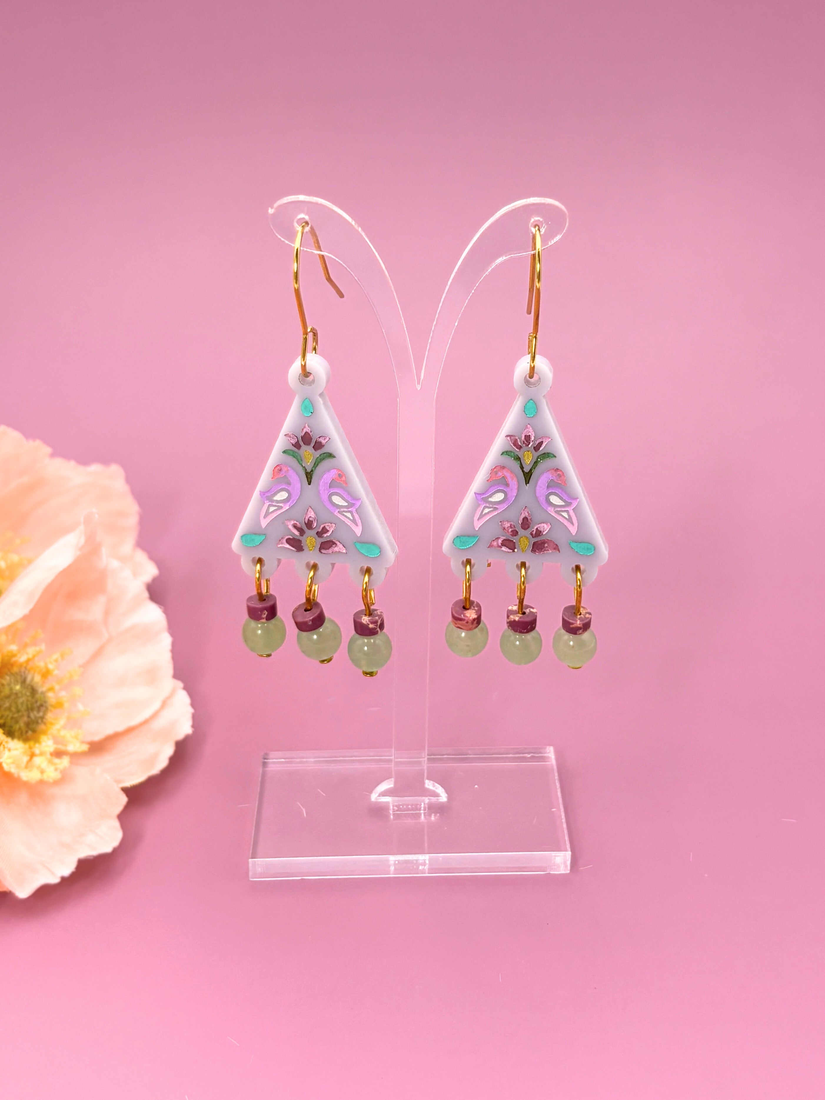 Triangular earrings with floral design on a pink background