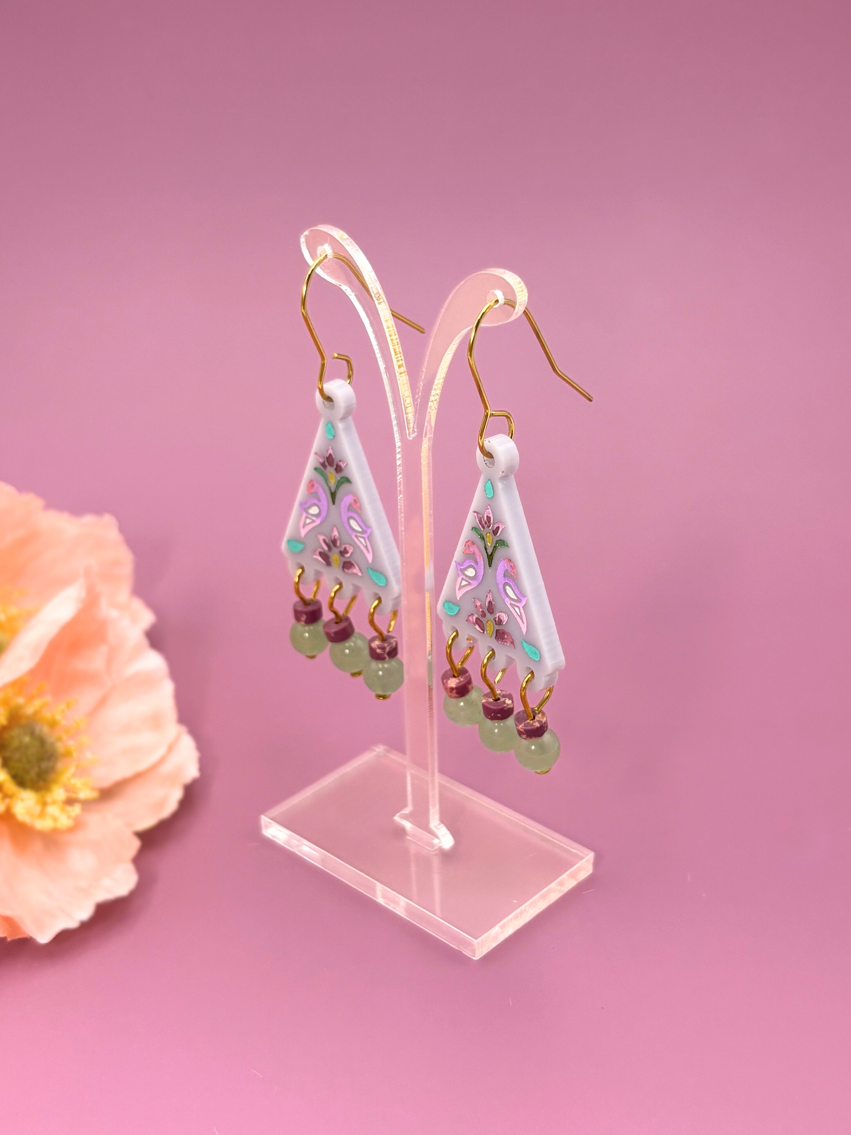 Decorative earrings on a stand with a pink background