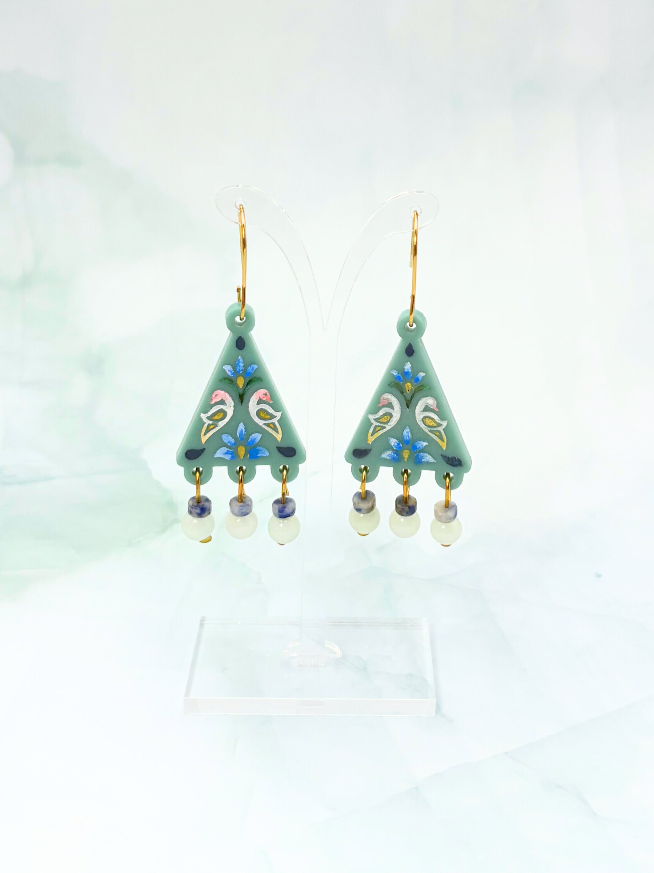 Decorative earrings with green triangular design on a light background