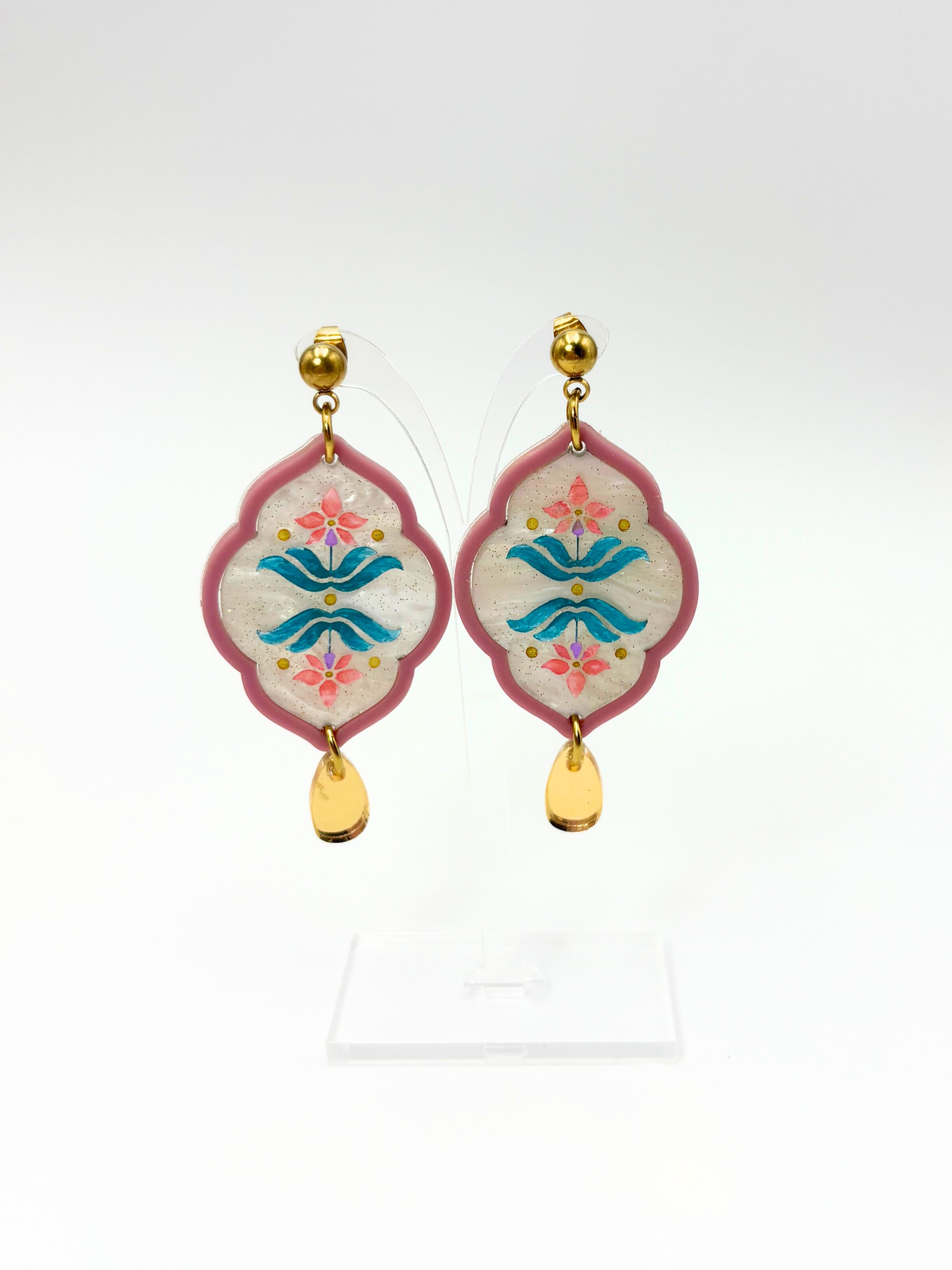Decorative earrings with floral and wave design on a white background