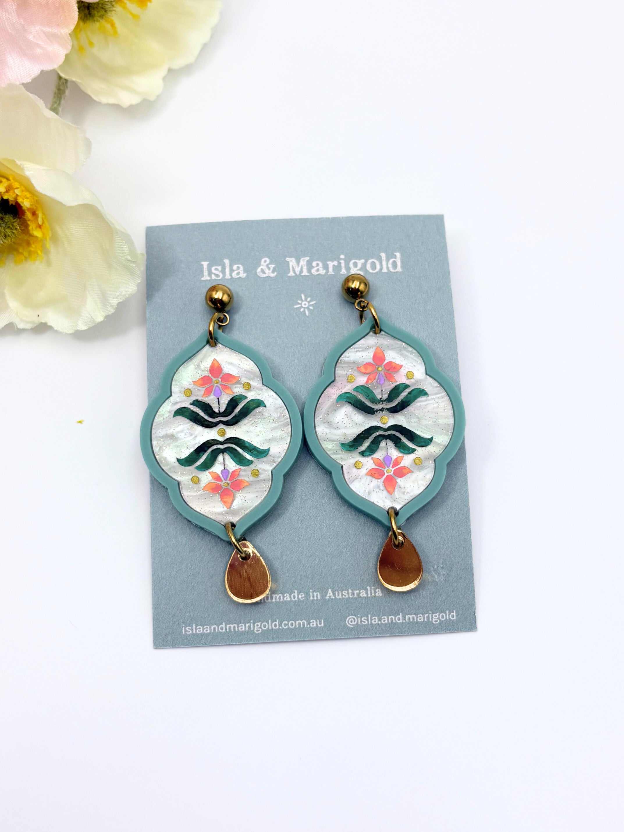 Decorative earrings with floral patterns on a green card branded Isla & Marigold with a white background