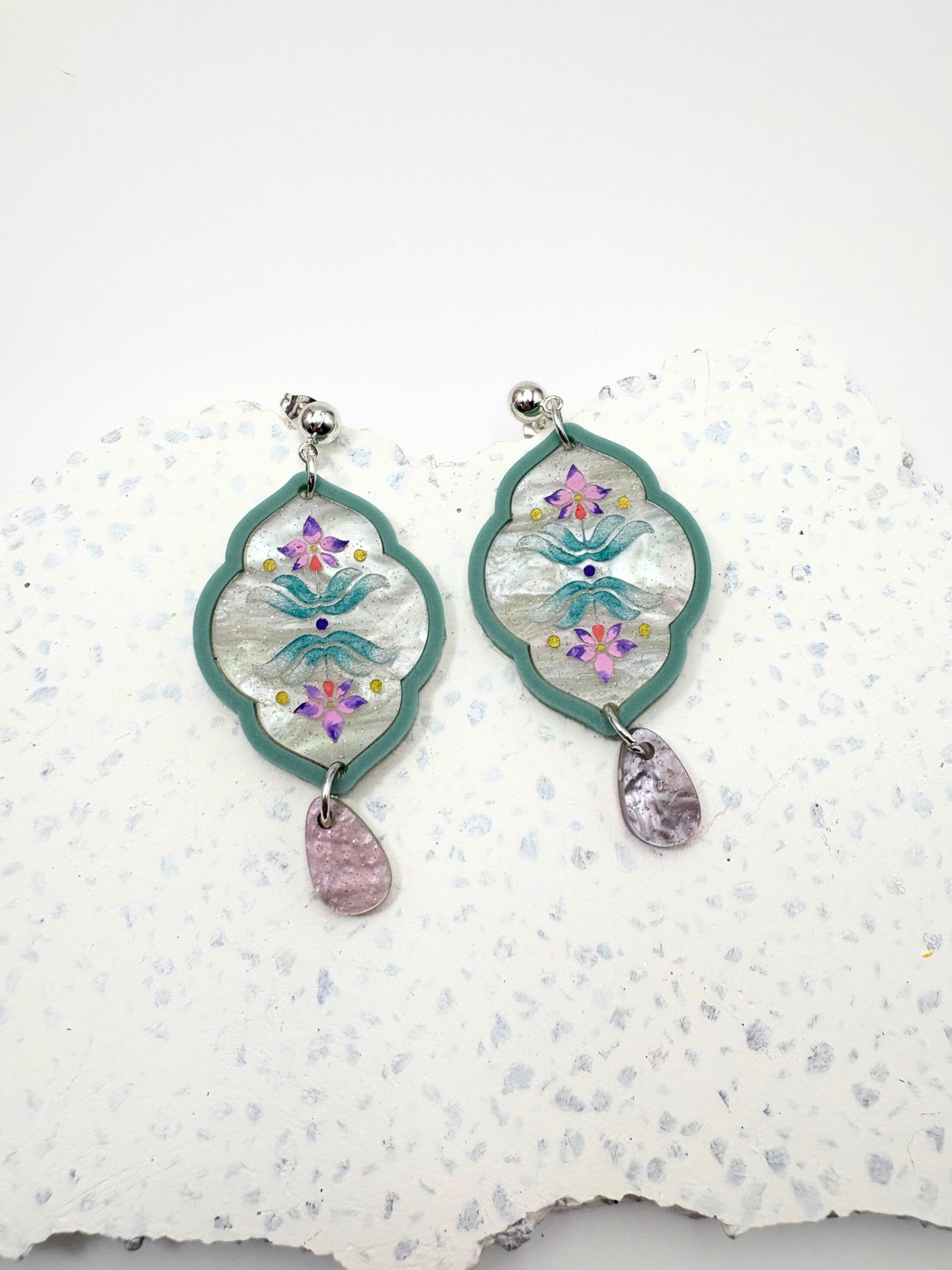 Decorative earrings with floral design on a textured white surface