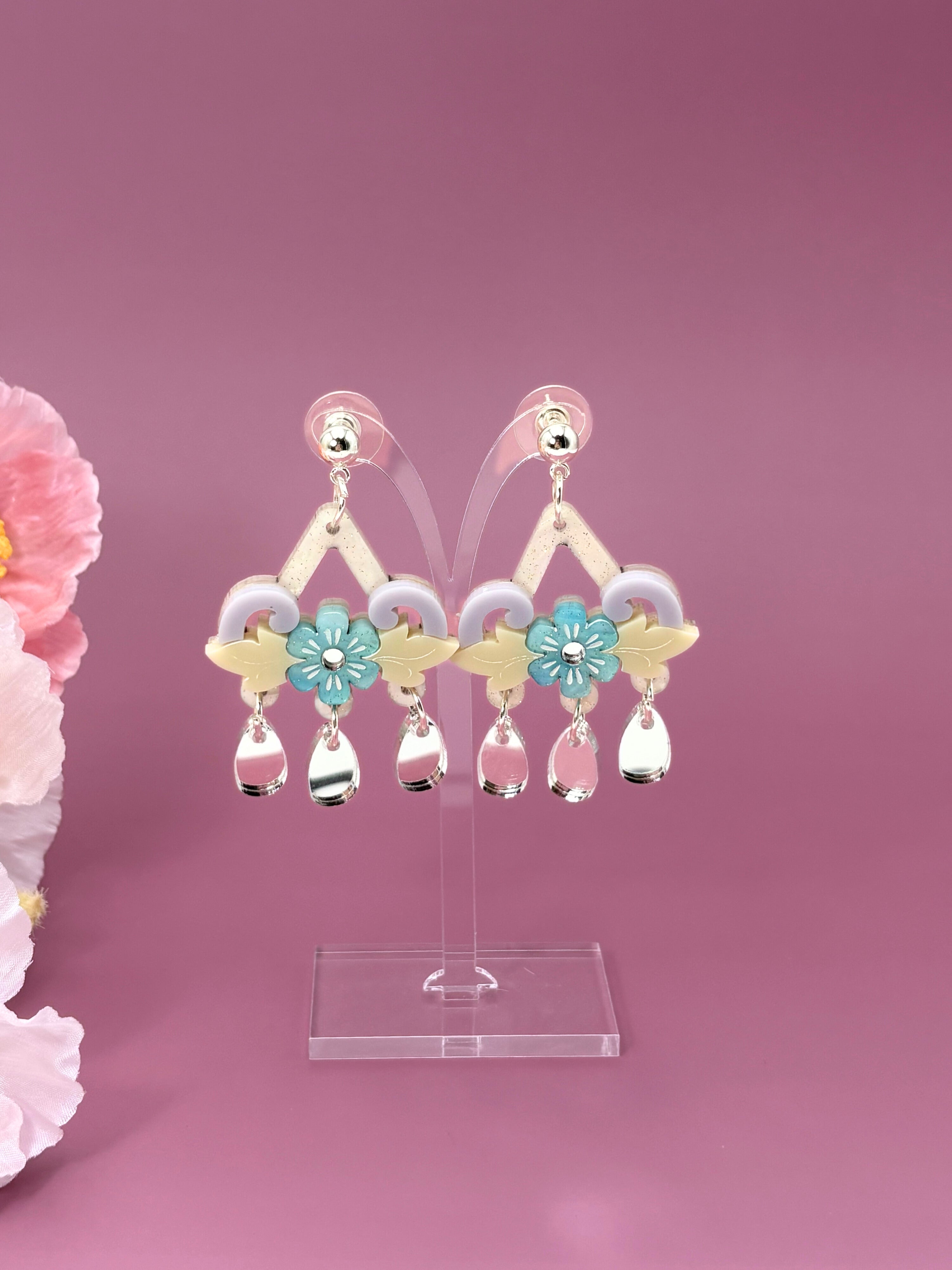 Pair of earrings with floral designs on a pink background
