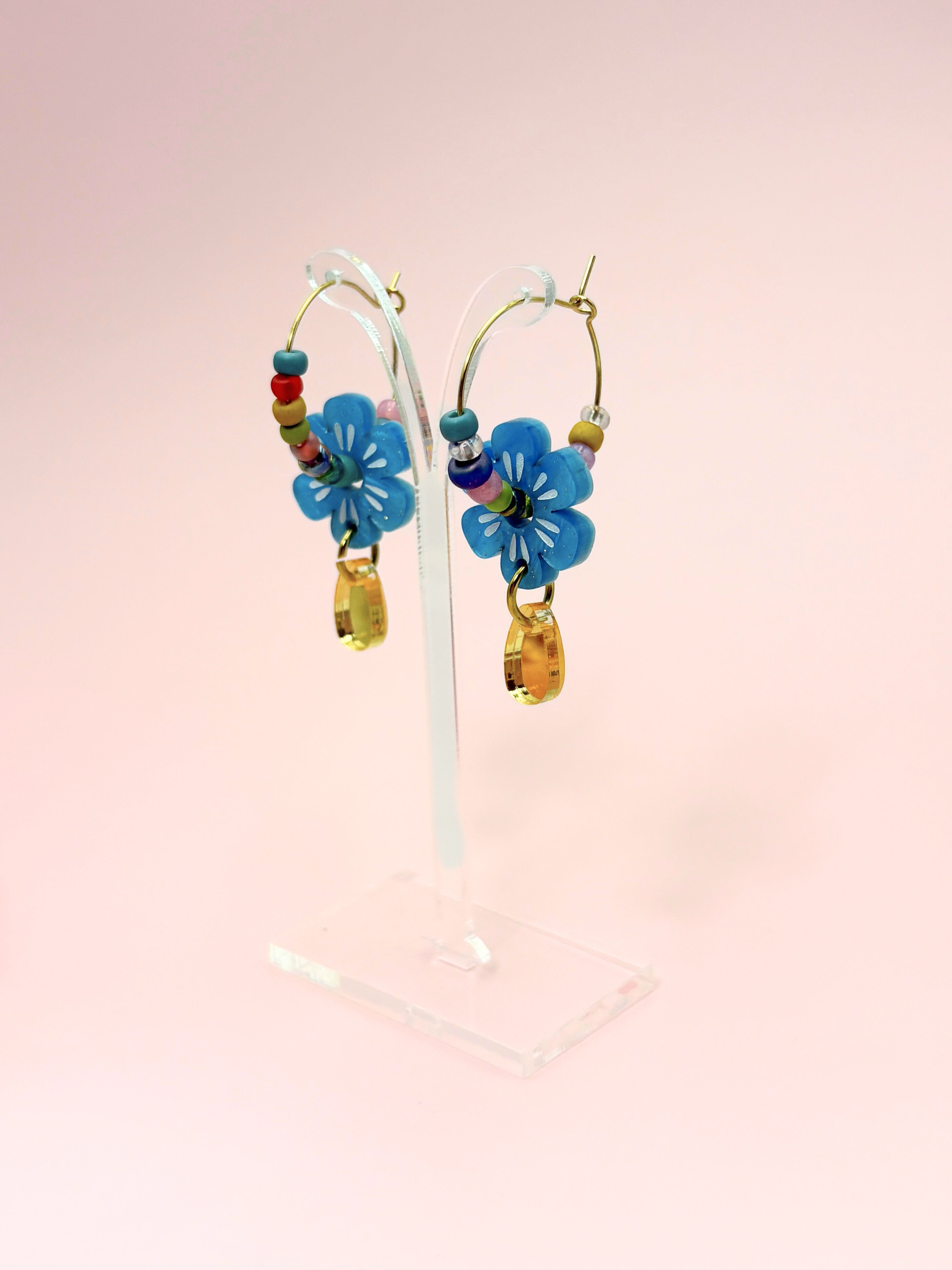 Colorful flower-shaped earrings on a pink background