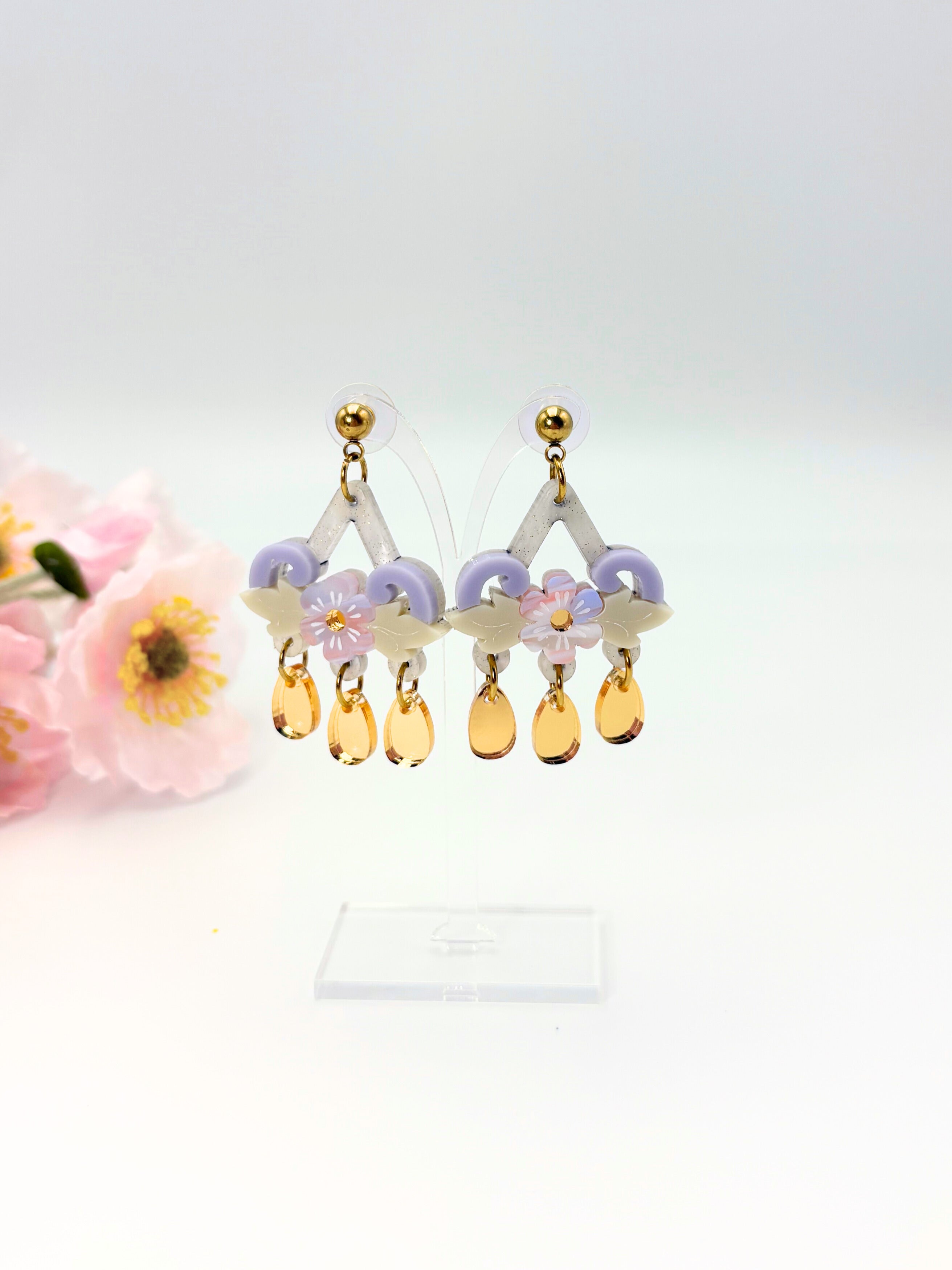Pastel-colored earrings with floral and teardrop designs on a white background