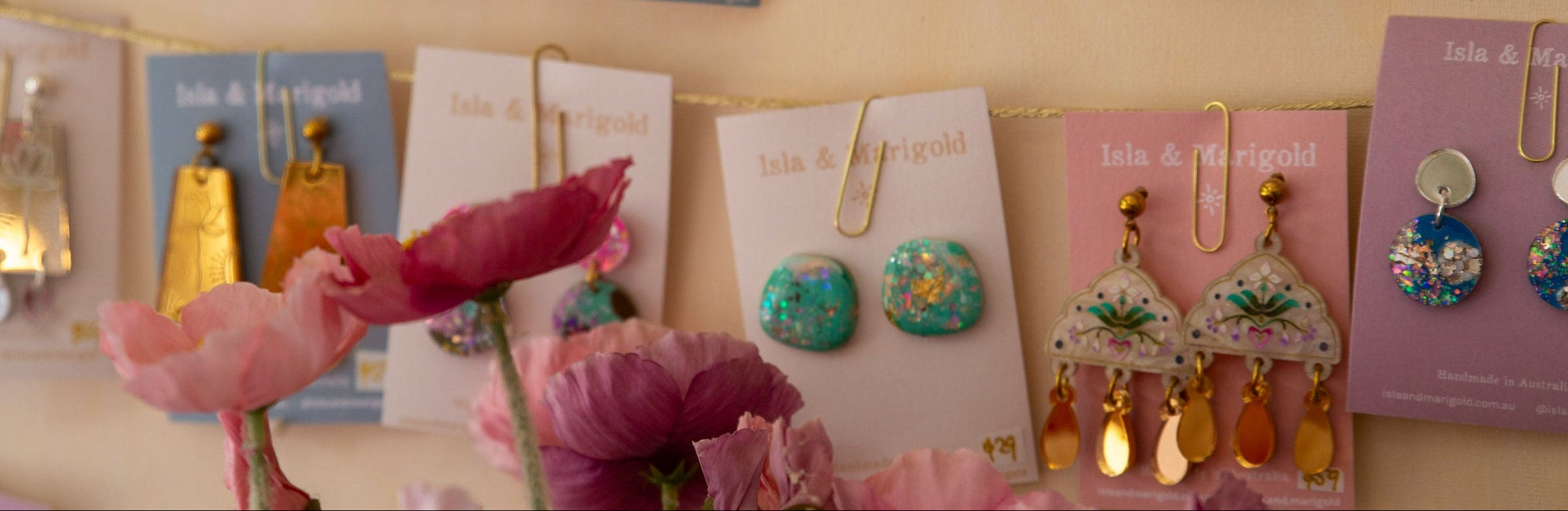 Display of colorful earrings on cards with flowers in the foreground.
