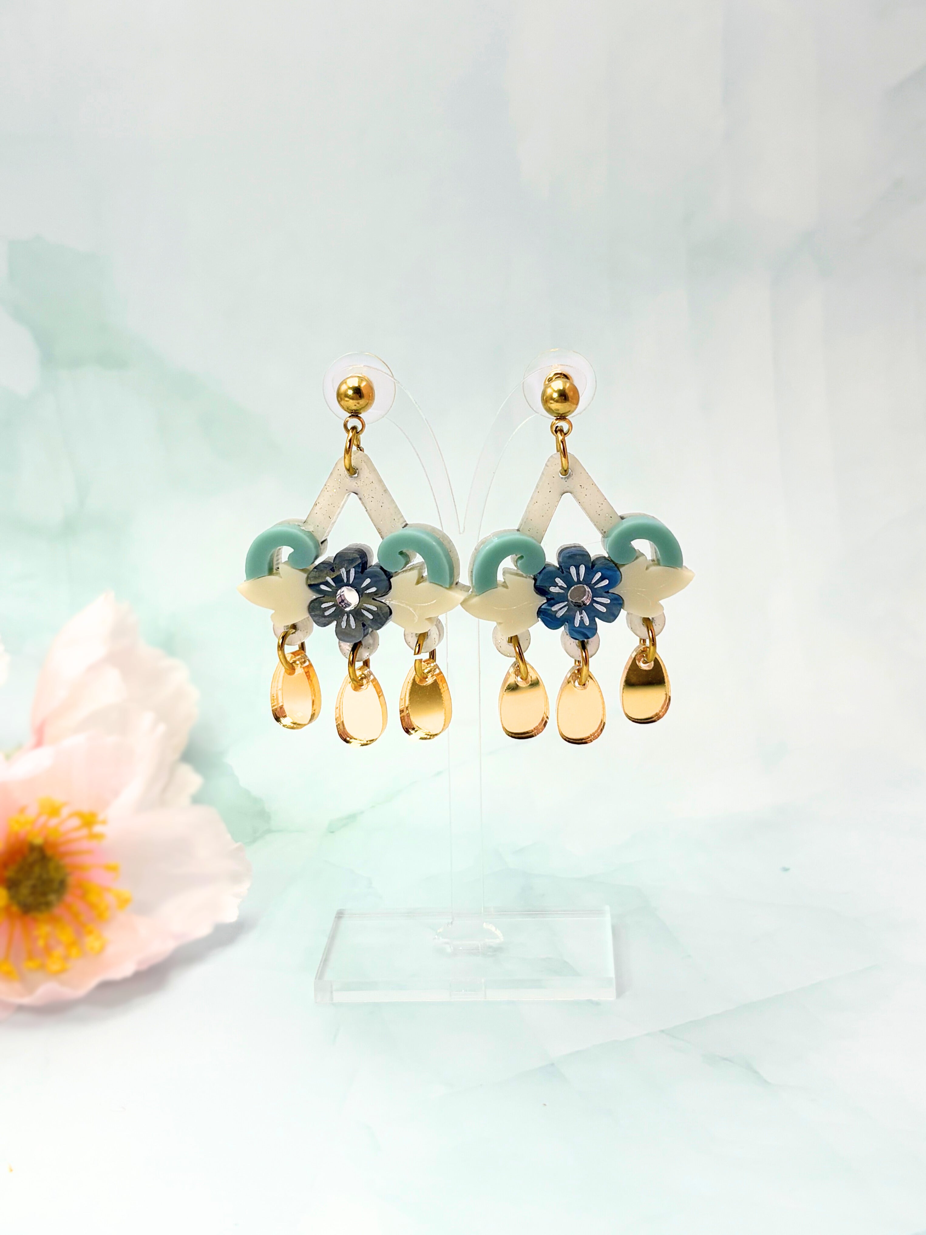 Decorative earrings with floral and teardrop designs on a light background
