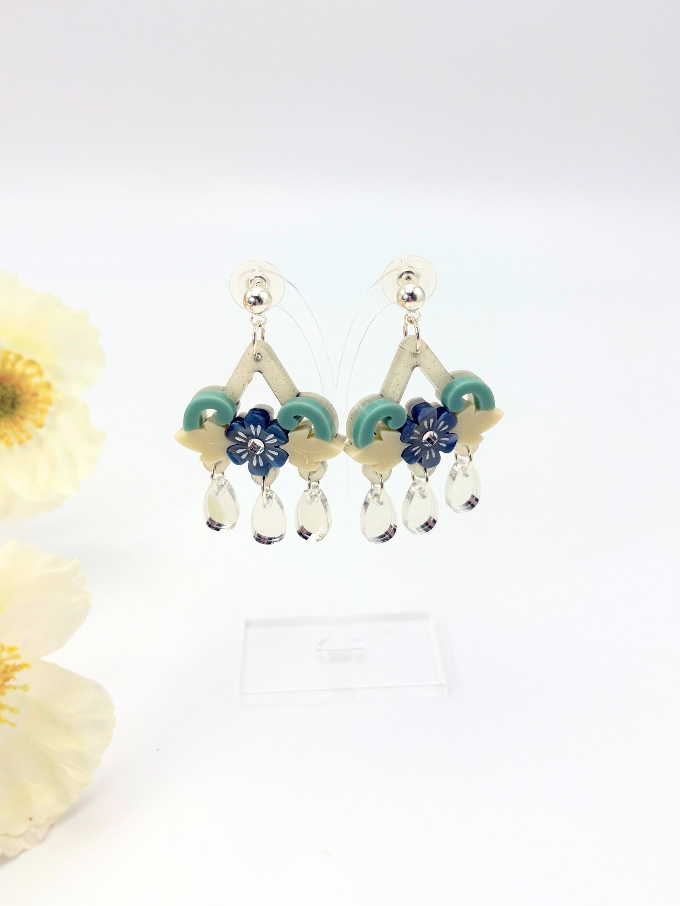 Pair of acrylic and solver stainless steel earrings with floral design on a white background